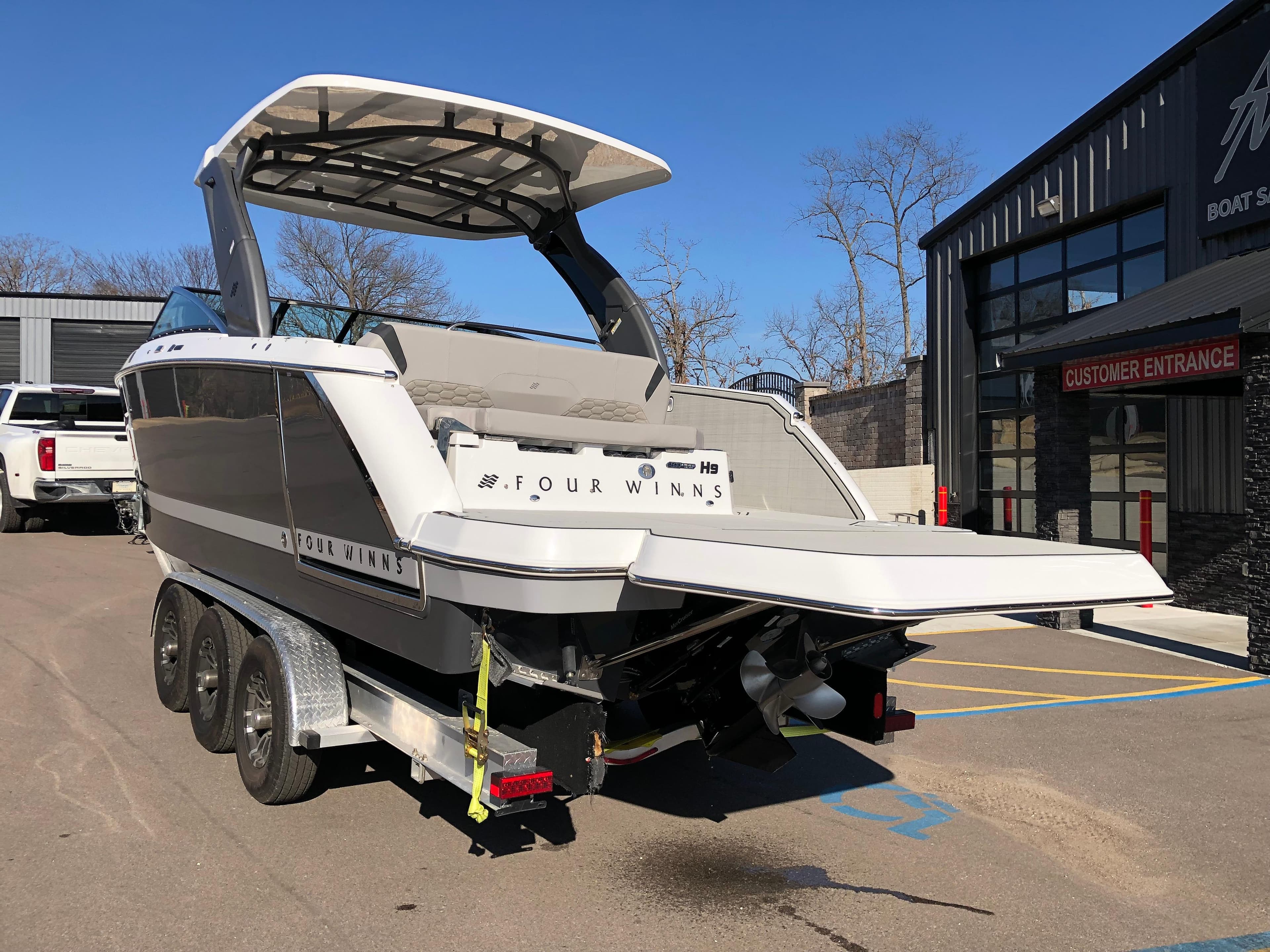 2025 Four Winns H9 boat on trailer outside dealership.