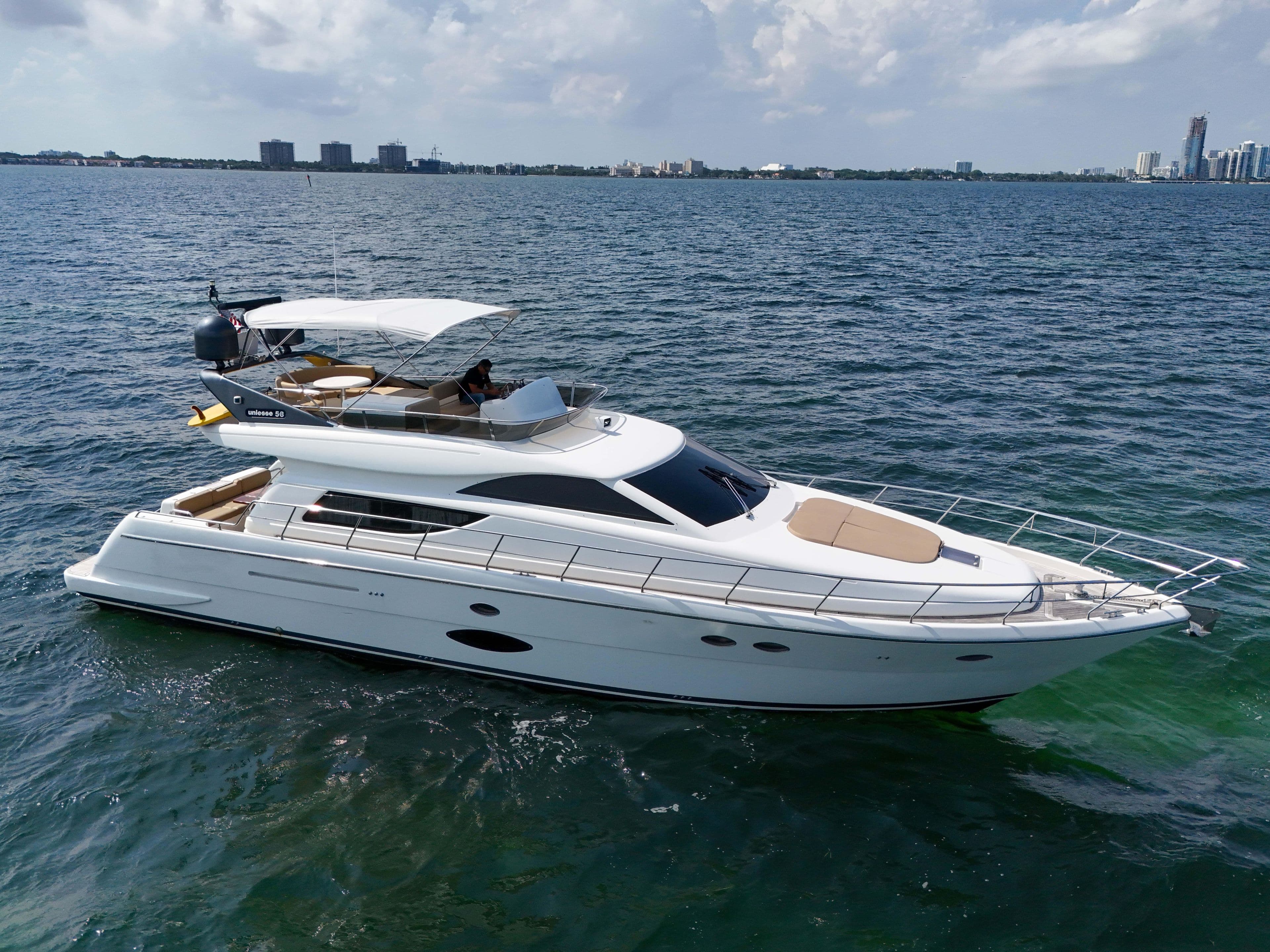 2006 Uniesse 58 yacht cruising on open water with city skyline in background.