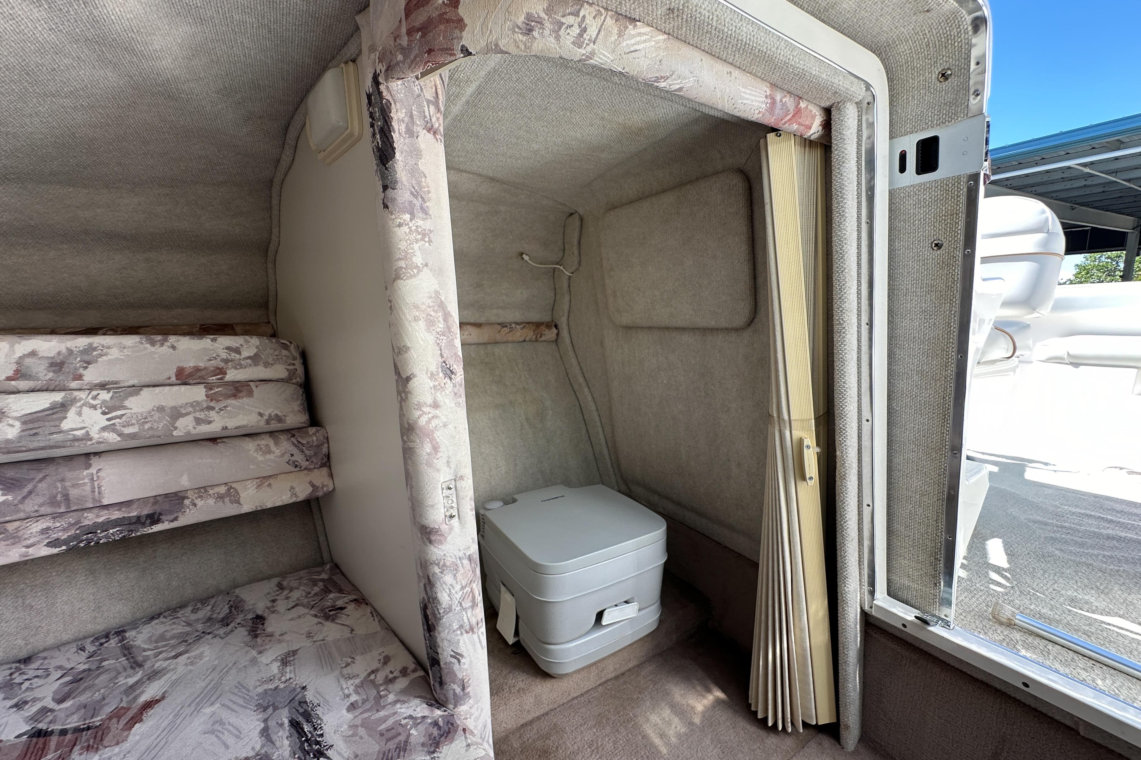 1998 Sea Ray 215 Express Cruiser interior with compact toilet and patterned cushions.
