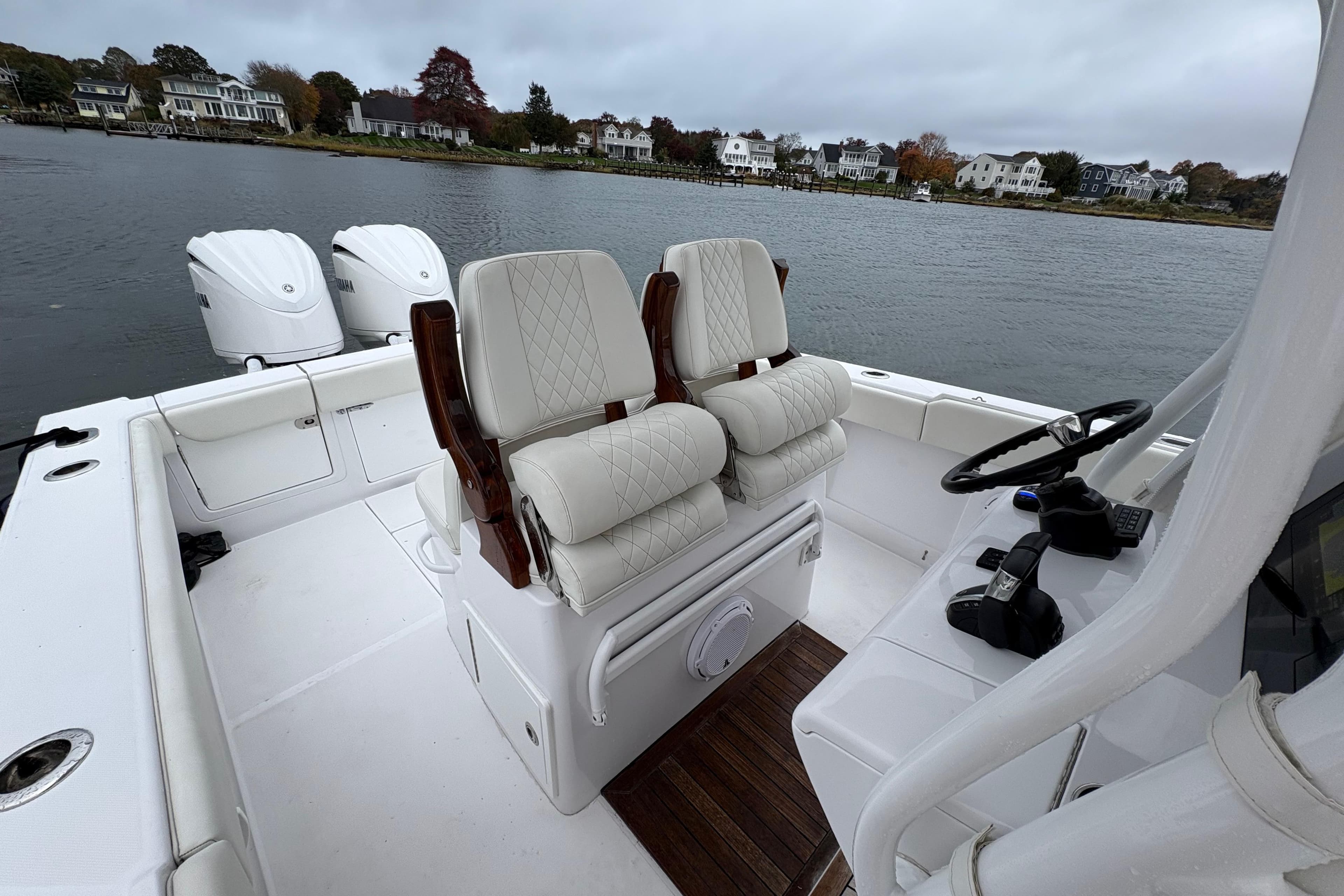 2023 Jupiter 30 boat interior with dual seats and twin engines on a calm lake.