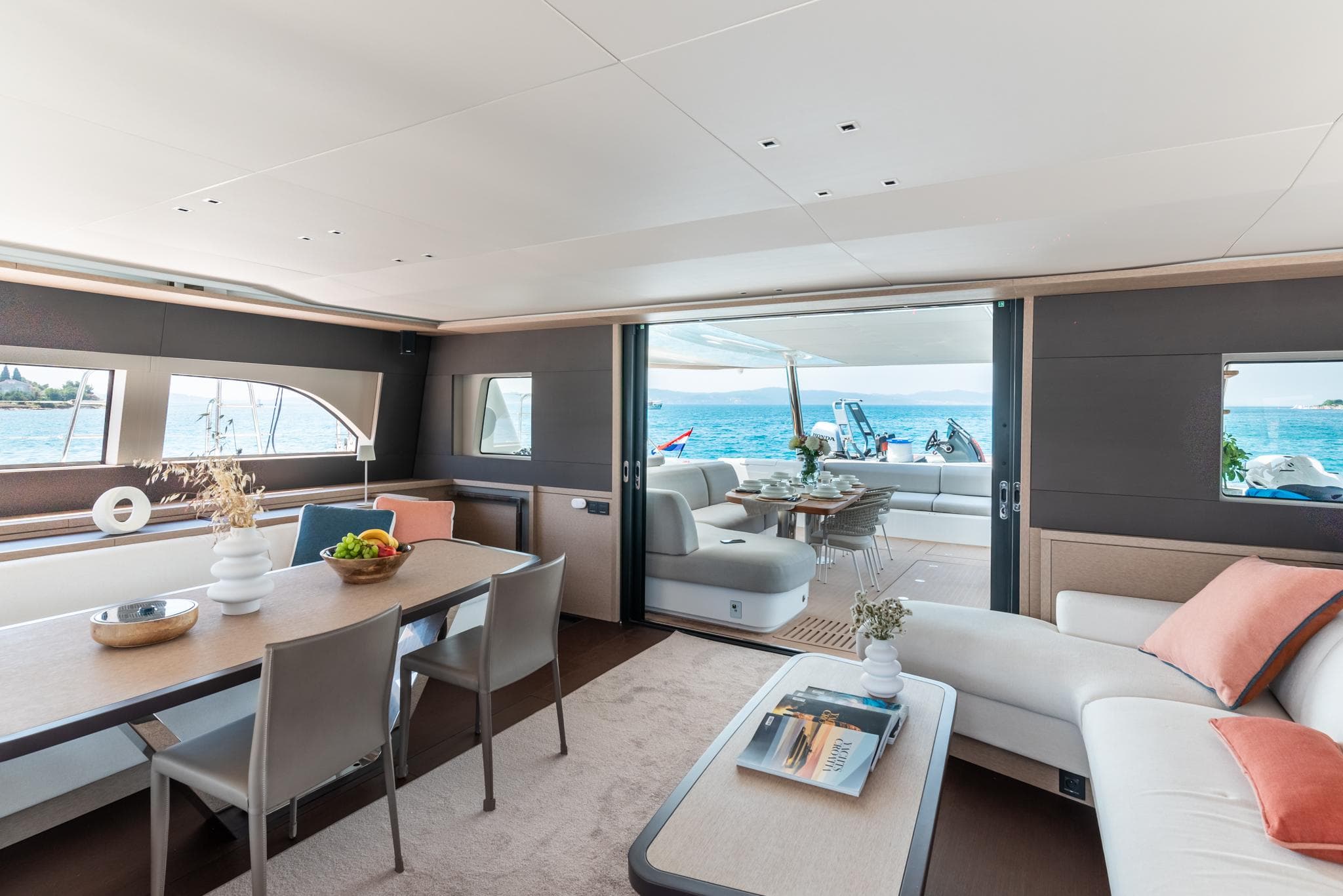 Luxurious interior of 2024 Lagoon SIXTY 5 yacht with ocean view and elegant furnishings.