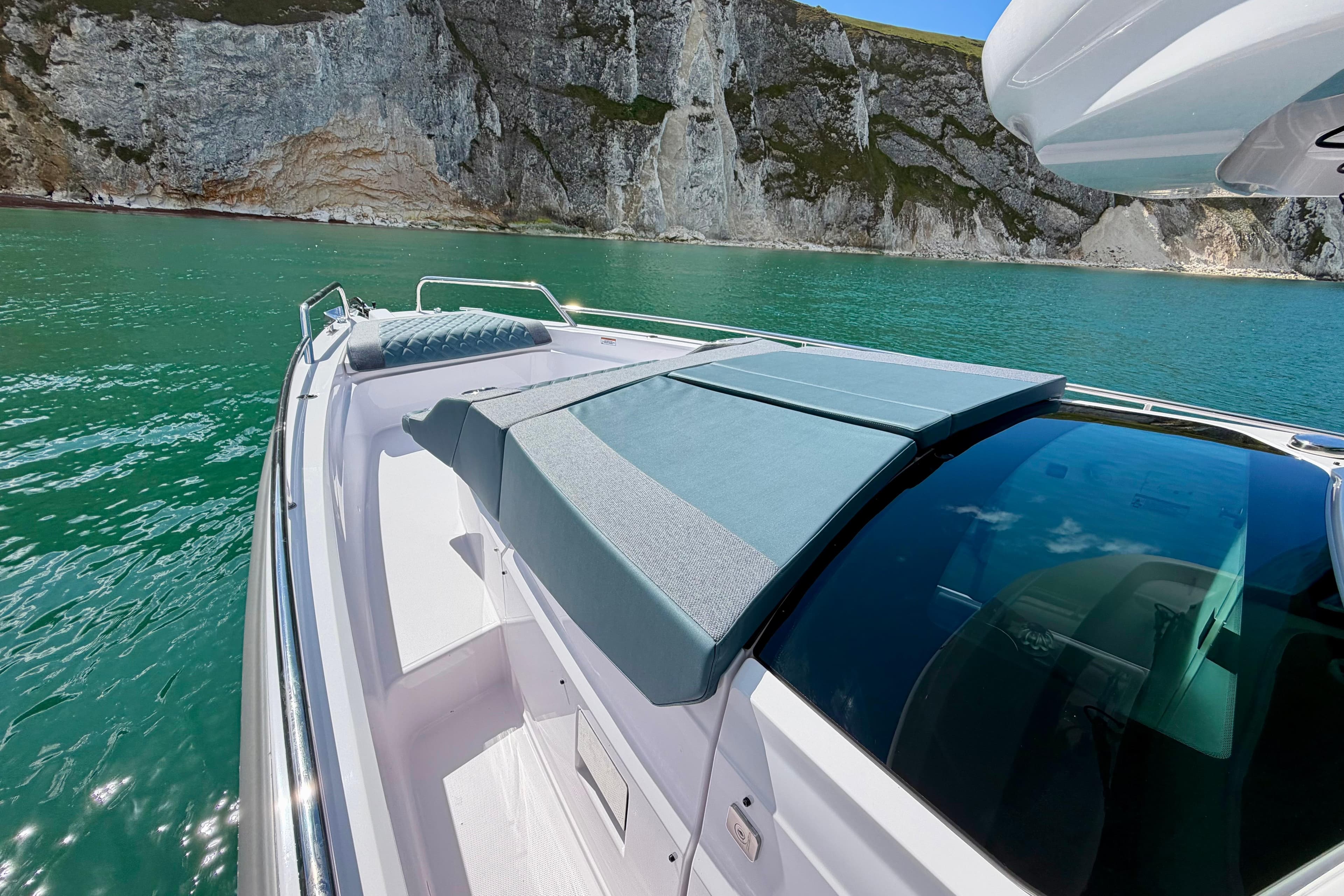 2024 Axopar 37 XC Cross Cabin on turquoise water near rocky cliffs.