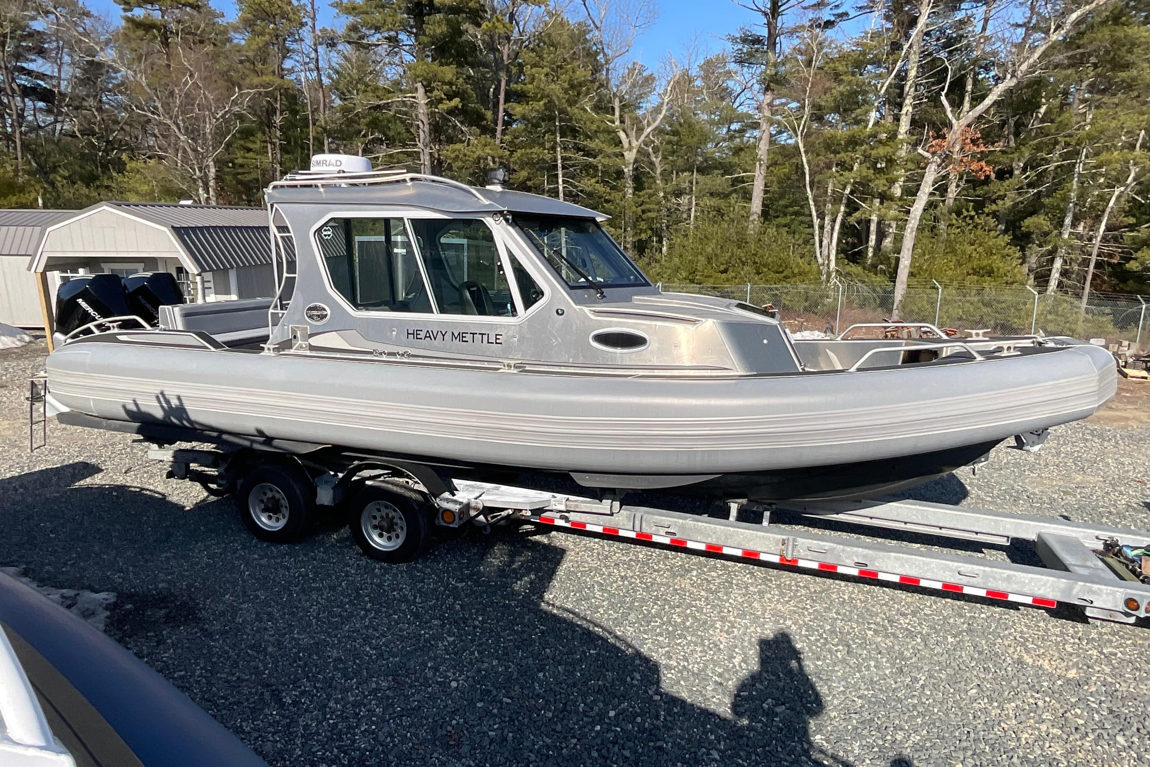 2025 Life Proof 31 GT Coupe boat on trailer, surrounded by trees and sheds.