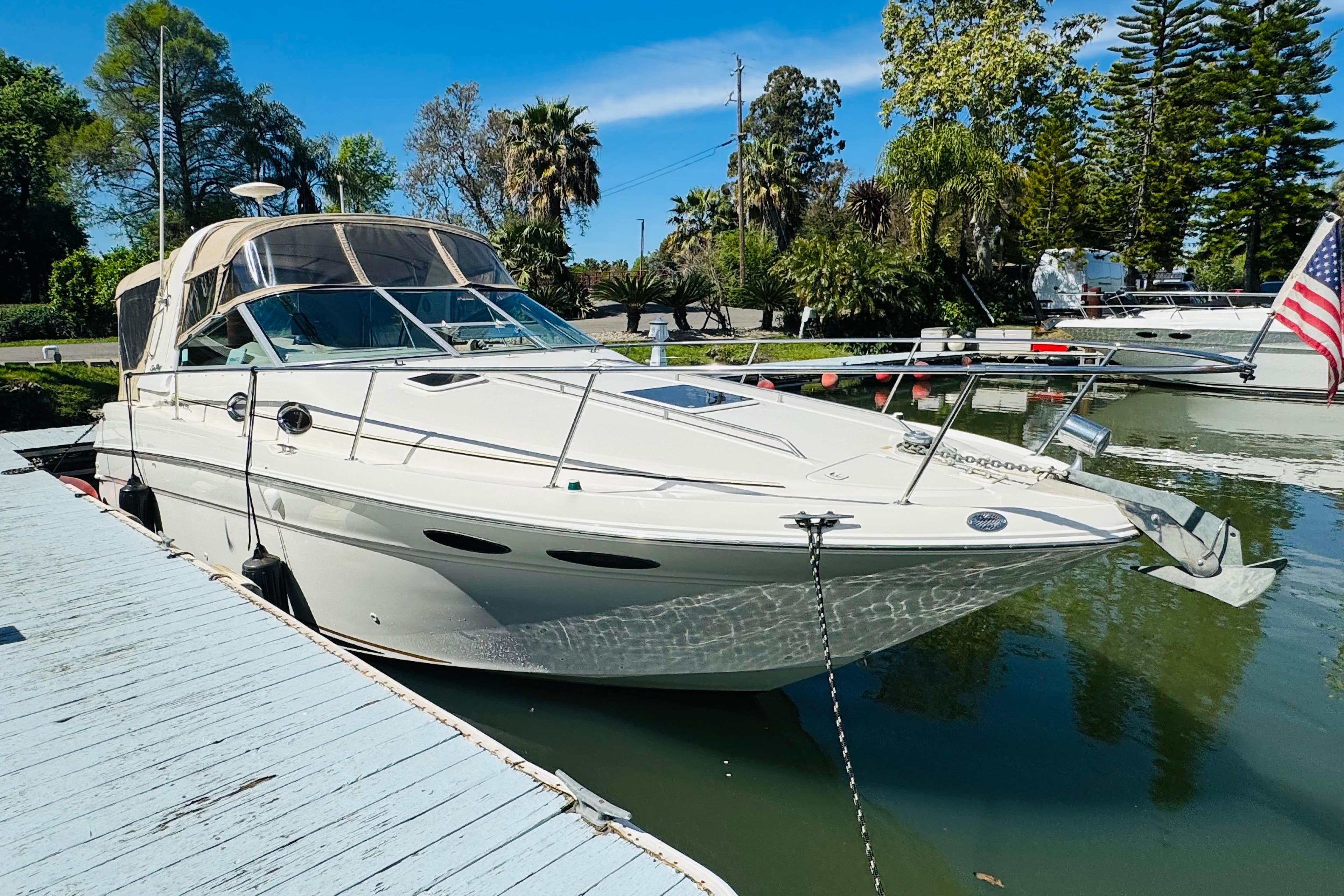 2000 Sea Ray 290 Sundancer docked, featuring sleek design and American flag.