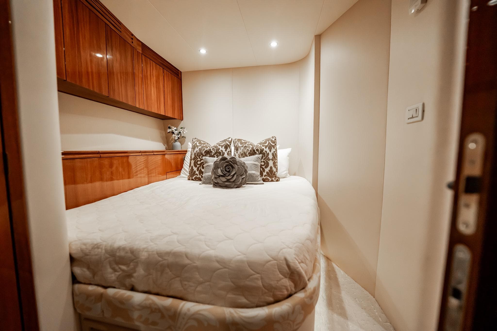 Luxurious bedroom interior on 2012 Hatteras 80 Motor Yacht with elegant bedding and wood cabinetry.