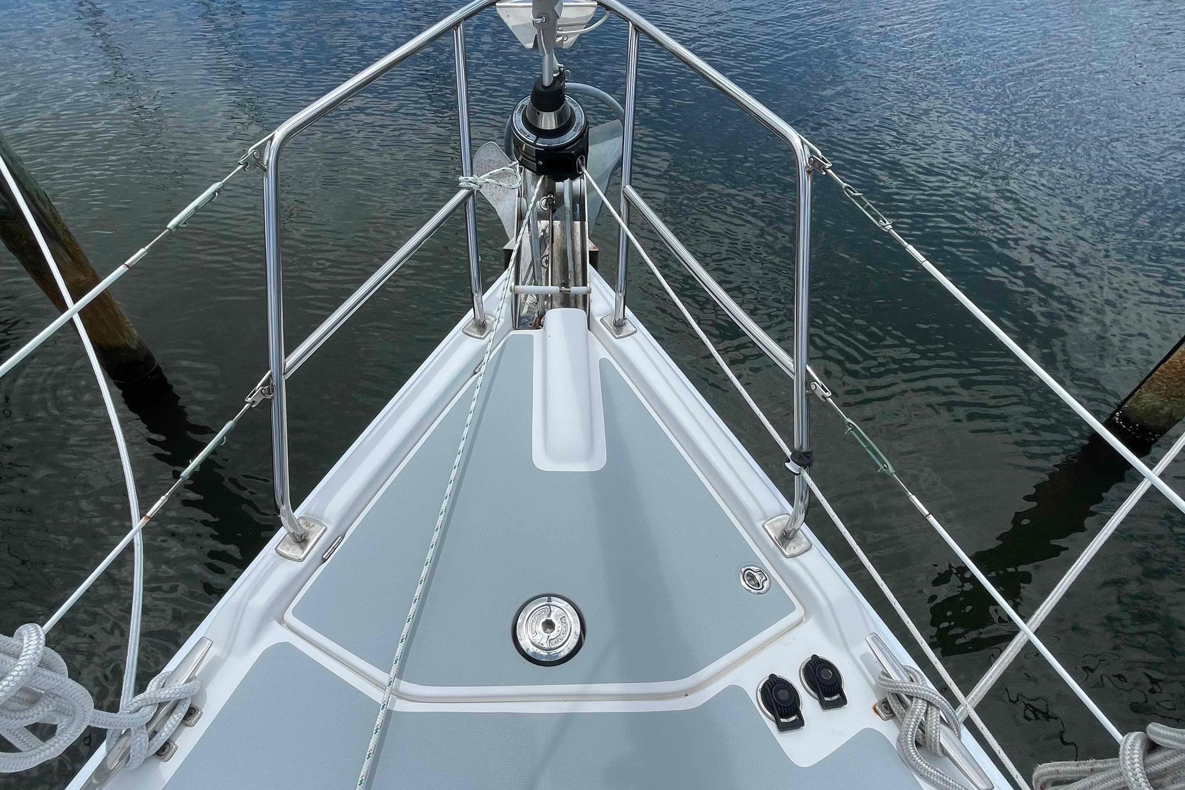 Bow of a 2004 Hunter 36 sailboat with stainless steel railings and calm water.