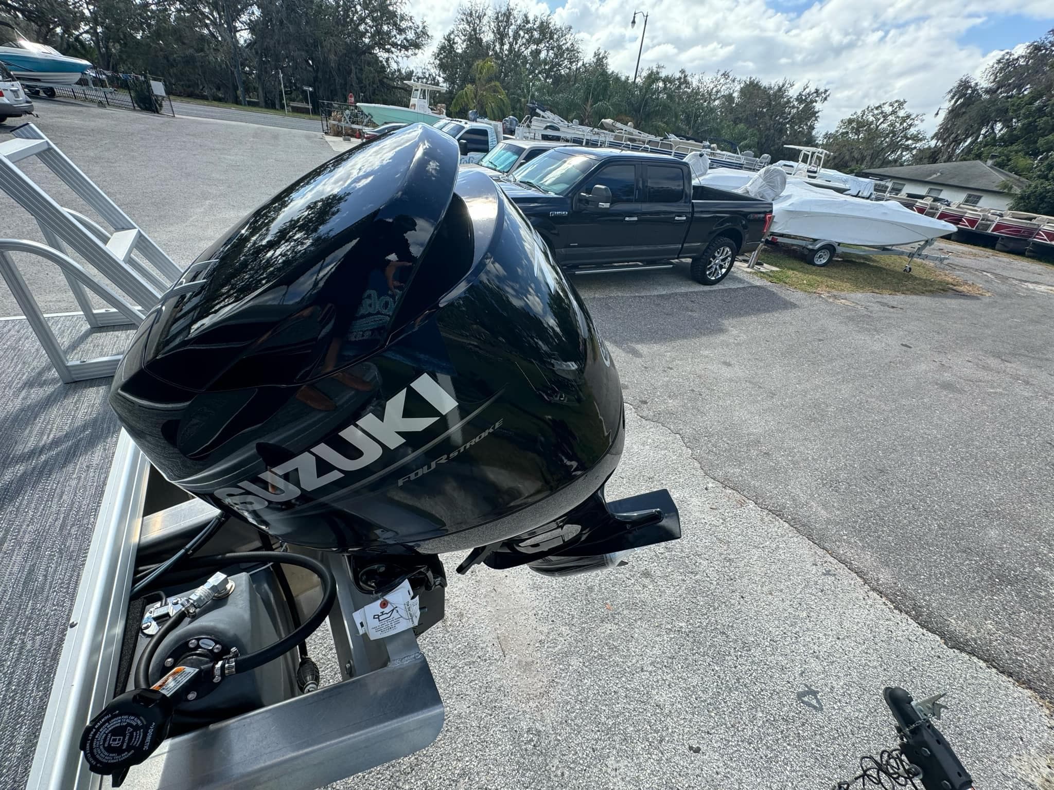 Suzuki outboard motor on Sweetwater 1886 CX boat, 2025 model, in a parking lot.