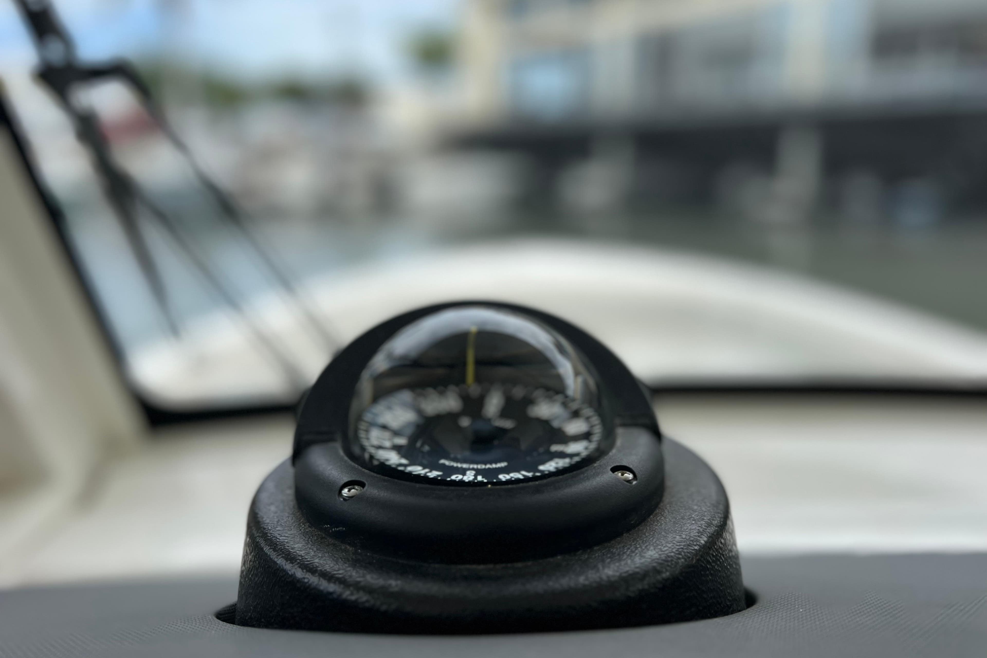Compass on 2022 Pursuit S 288 Sport boat dashboard, blurred marina background.