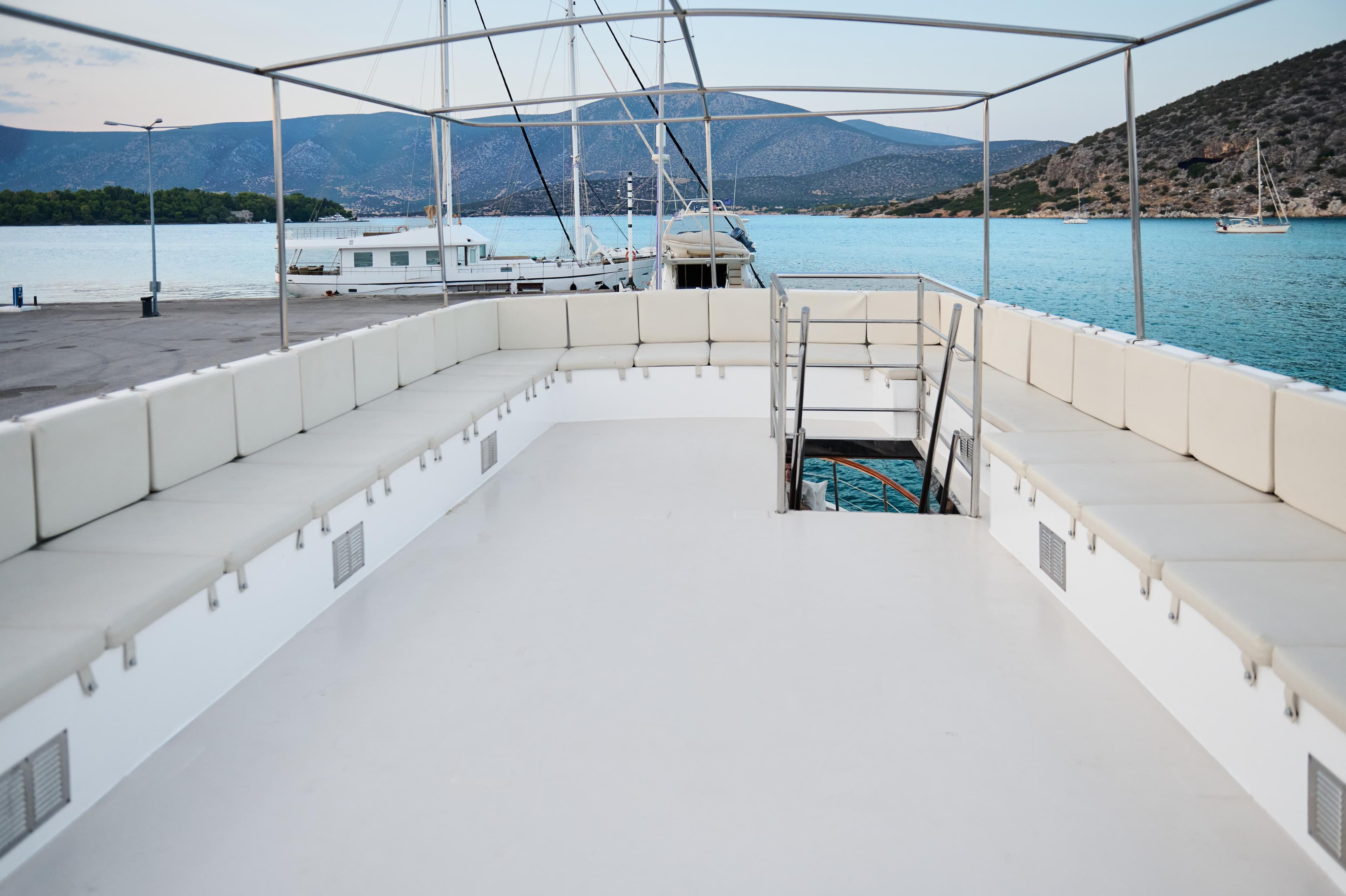 Spacious deck of a 1960 Burger 85 yacht, docked with scenic mountain views.