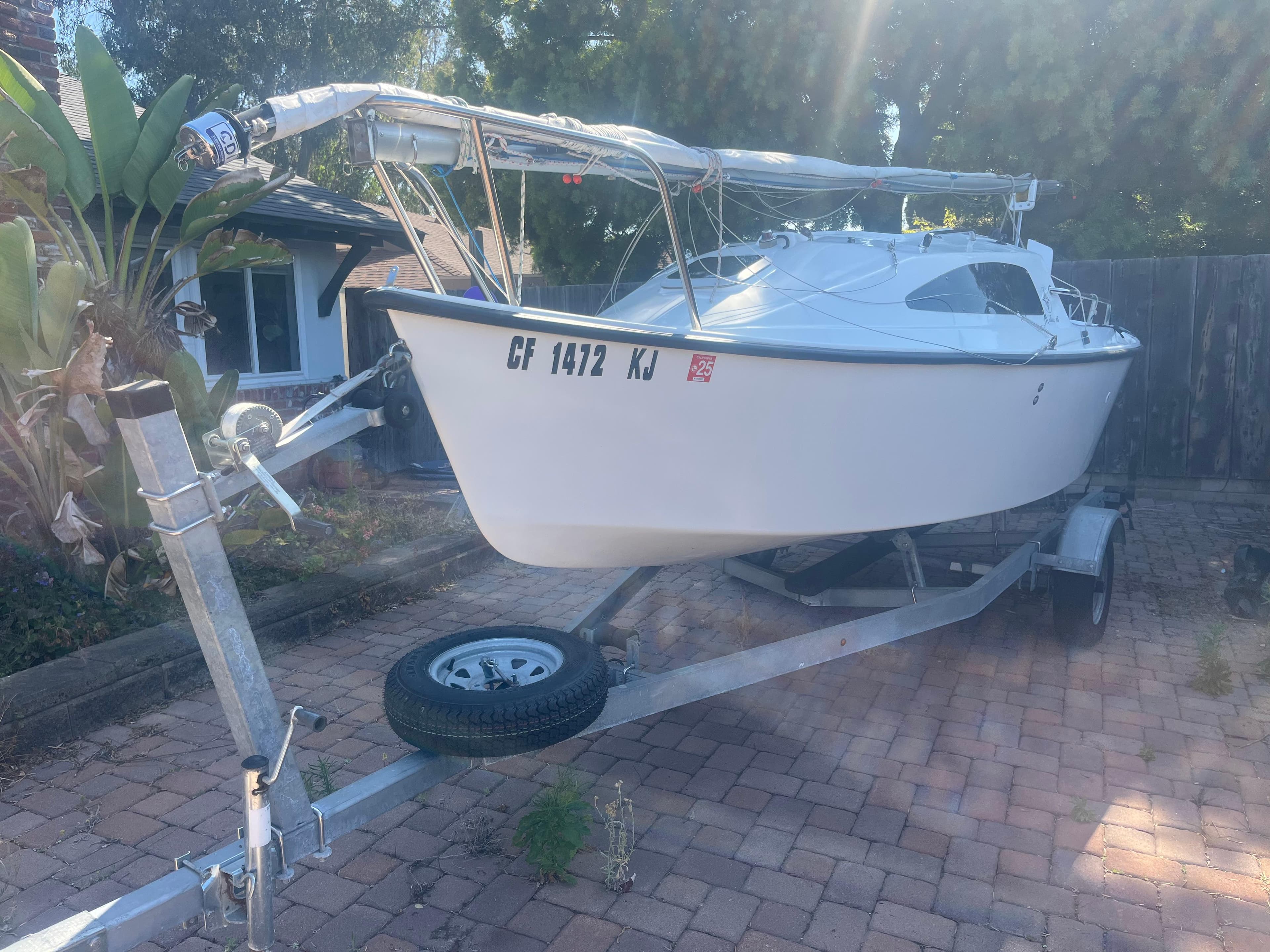 Sailboat on trailer, Malbec 18 model, 2023, parked on brick driveway.