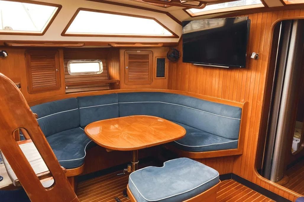 Luxurious interior of a 1999 Hylas 54 yacht with wood paneling and blue seating.