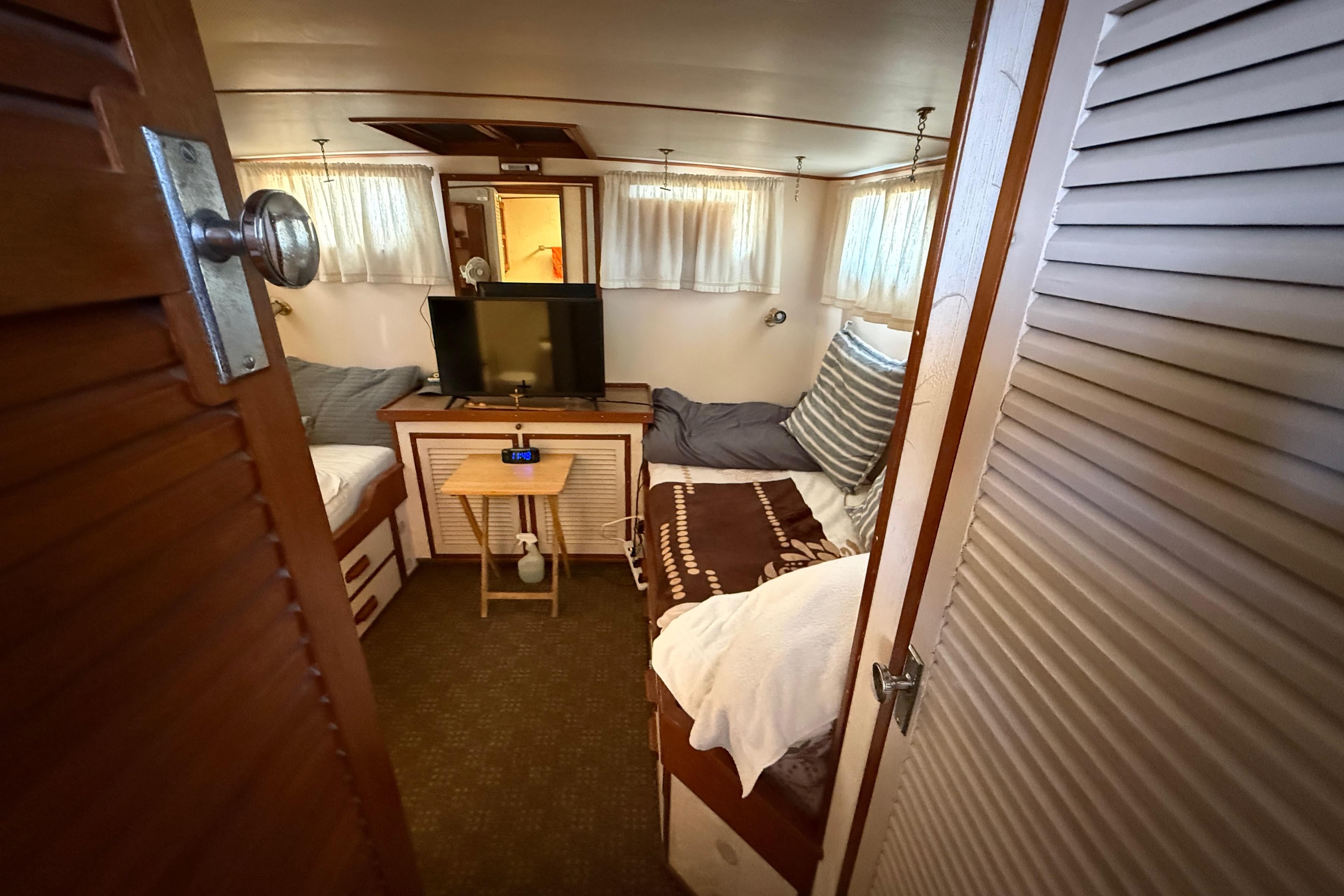 Cozy 1967 Jones-Goodell ACMY boat cabin with beds, TV, and wooden decor.