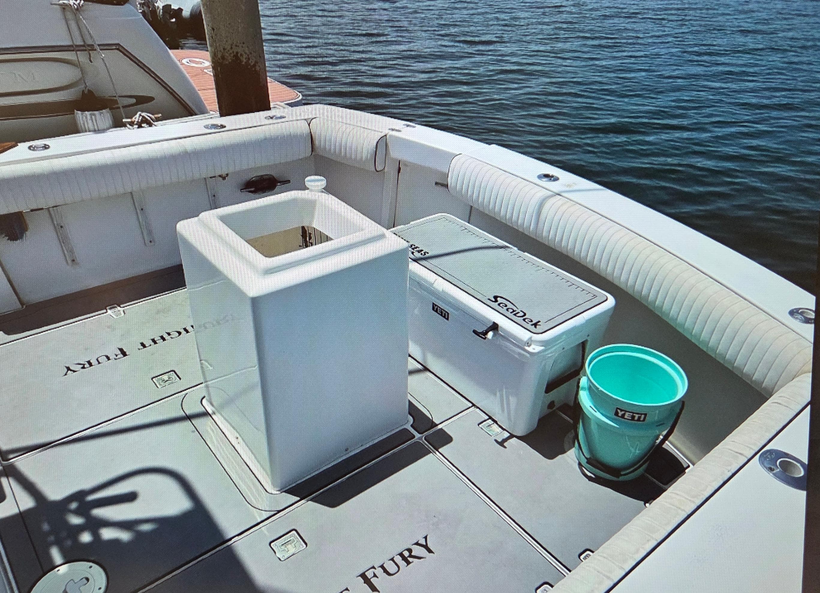 2001 Knight & Carver 33 SportFisherman deck with cooler and bucket, docked by the water.