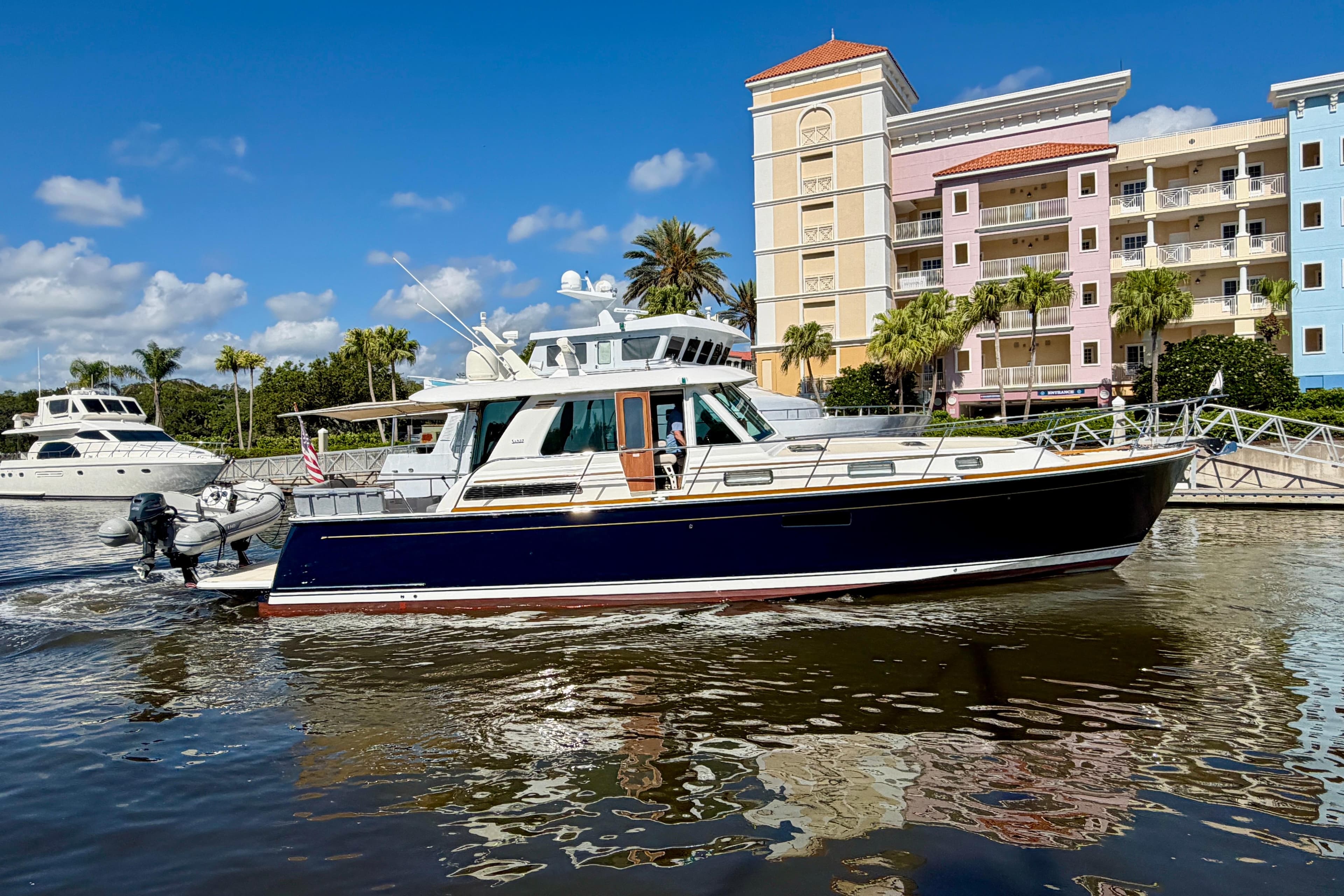 2016 Sabre 48 Salon Express yacht cruising near colorful waterfront buildings.