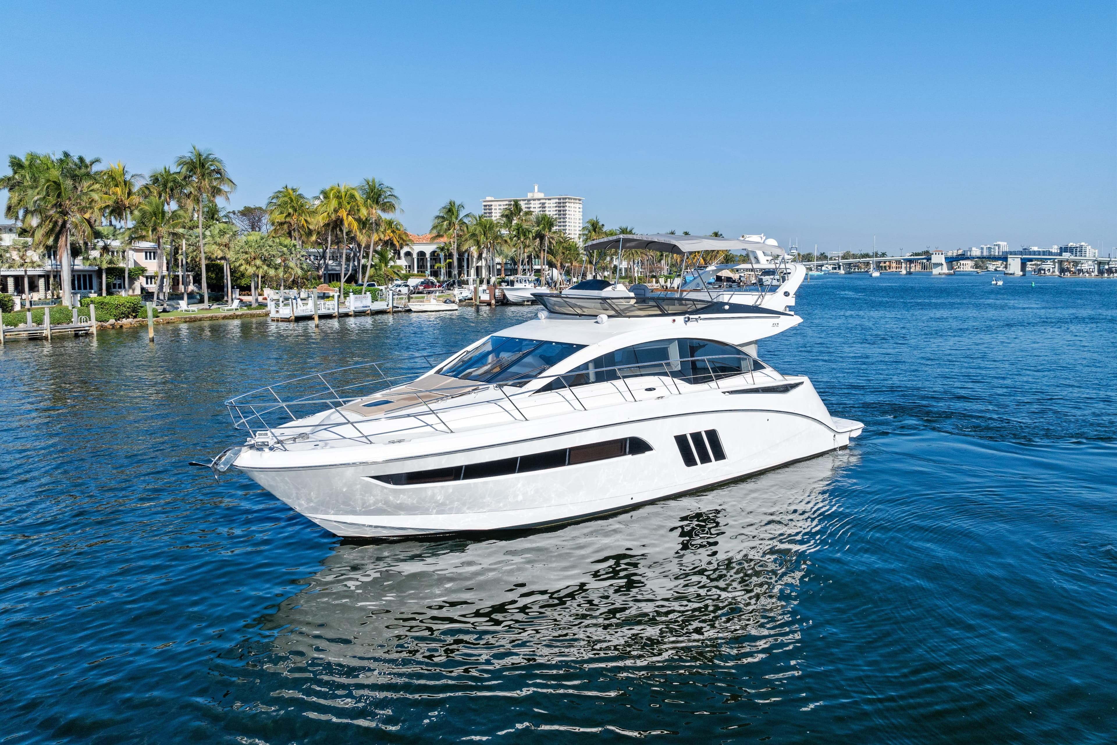 2014 Sea Ray 510 Fly yacht cruising on a sunny day near palm-lined shore.