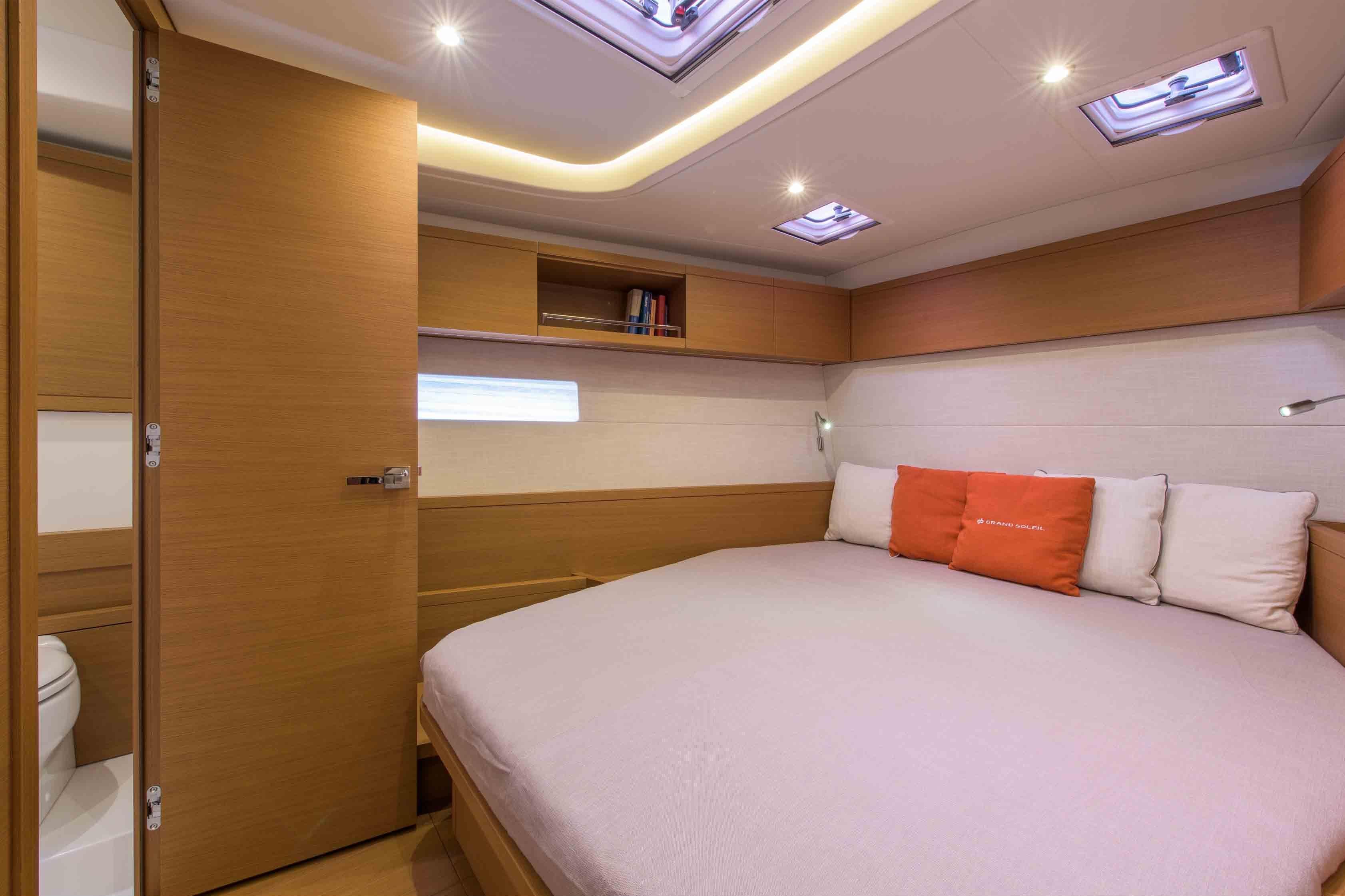 Luxurious cabin interior of 2025 Grand Soleil 52 LC yacht with cozy bed and modern lighting.