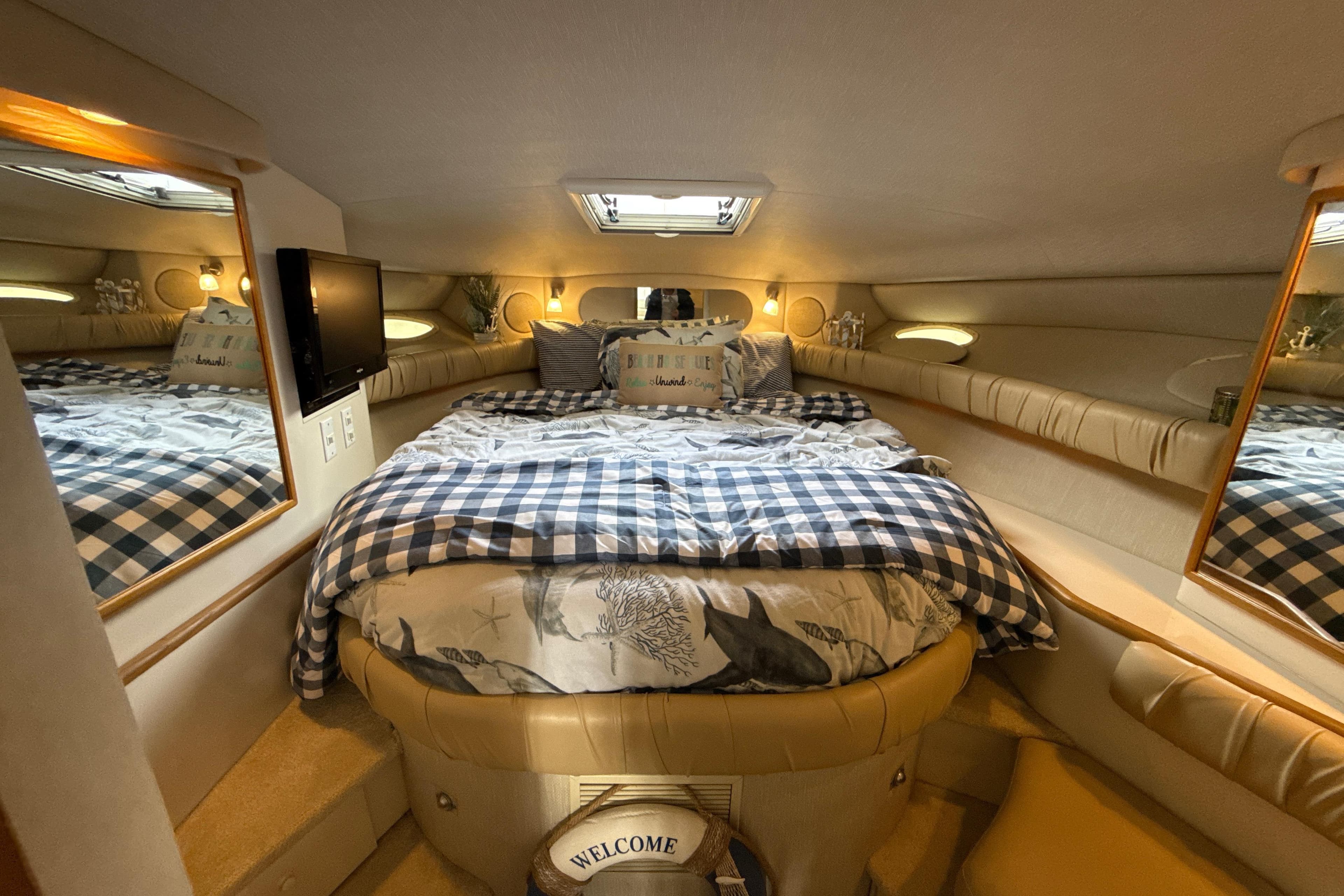 Cozy cabin interior of 1995 Sea Ray Sundancer 370 with bed, mirrors, and decor.