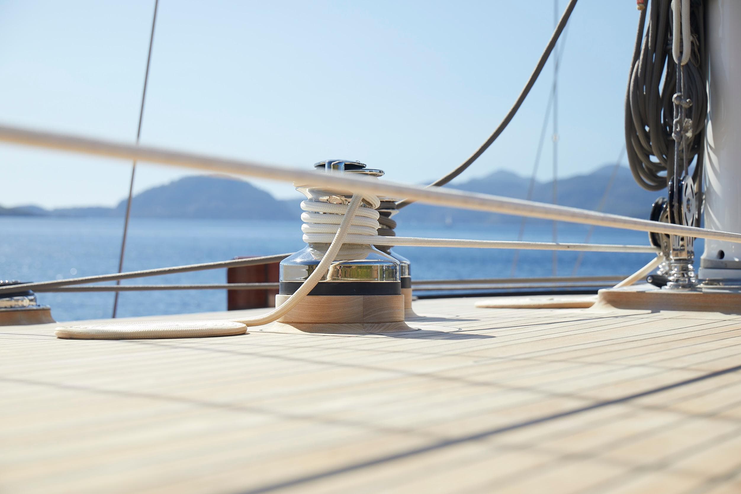 Custom 2020 schooner deck with winch, ropes, and scenic ocean view.