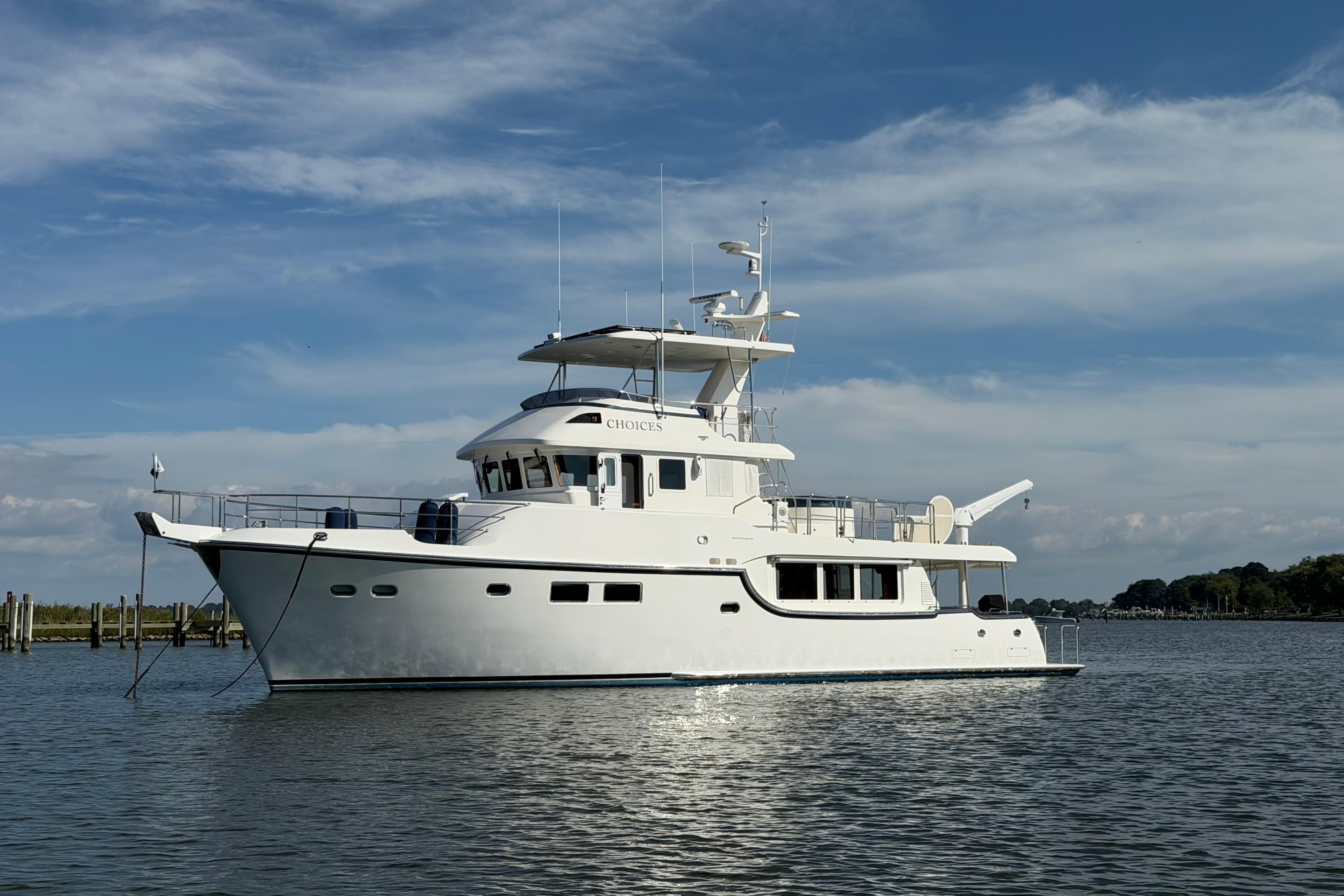 2016 Nordhavn 60 yacht on calm water under a clear blue sky.
