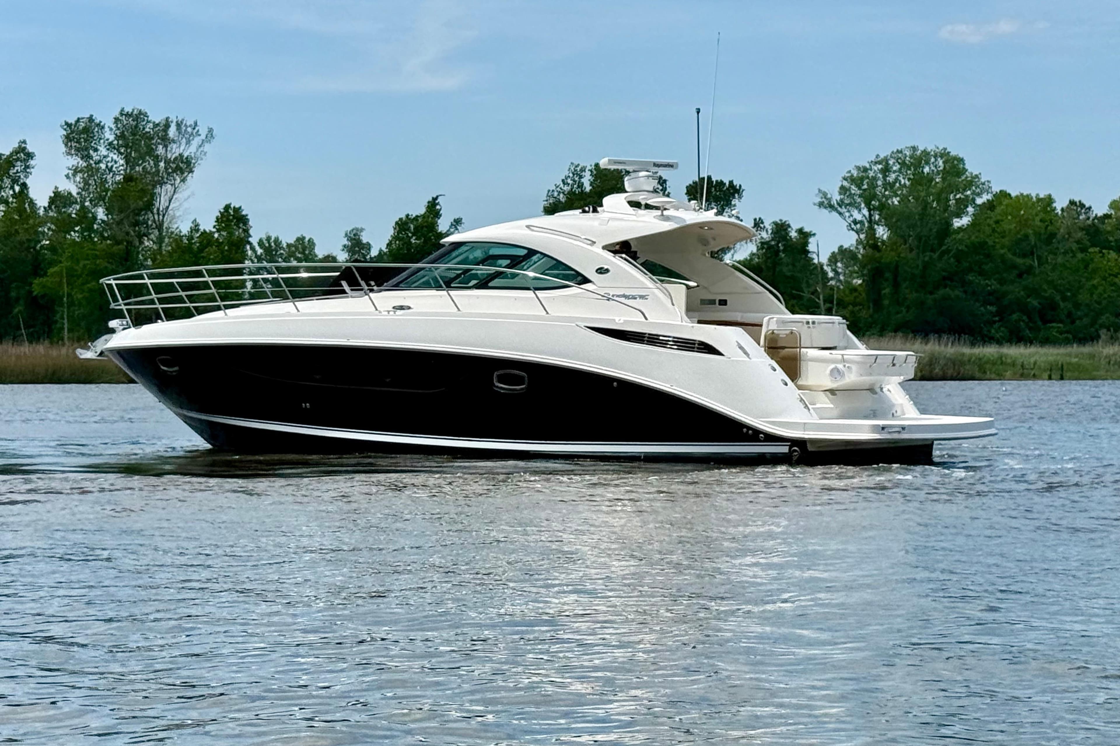 2012 Sea Ray 410 Sundancer yacht on calm water, surrounded by lush greenery.