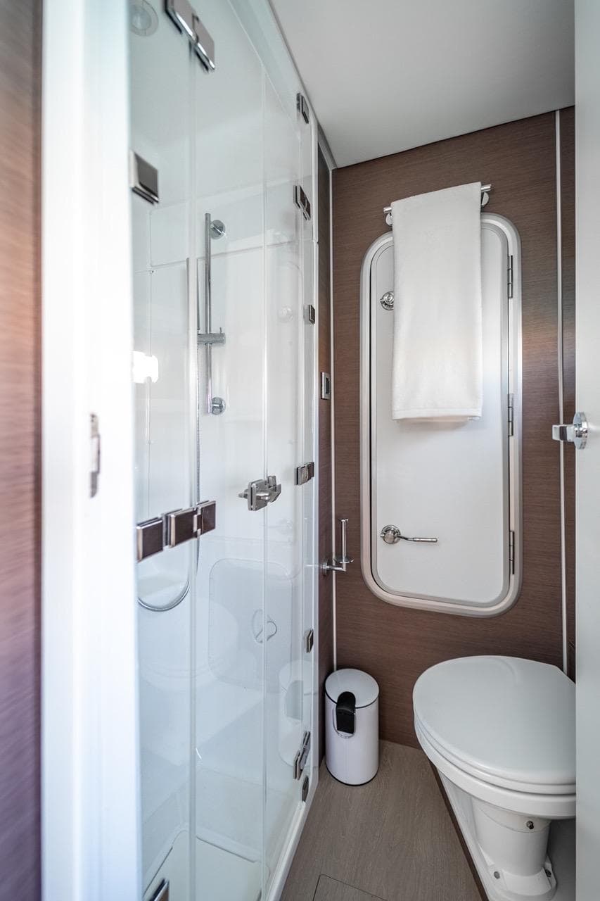 Modern yacht bathroom with glass shower, toilet, and towel rack. Bali 5.4, 2021 model.