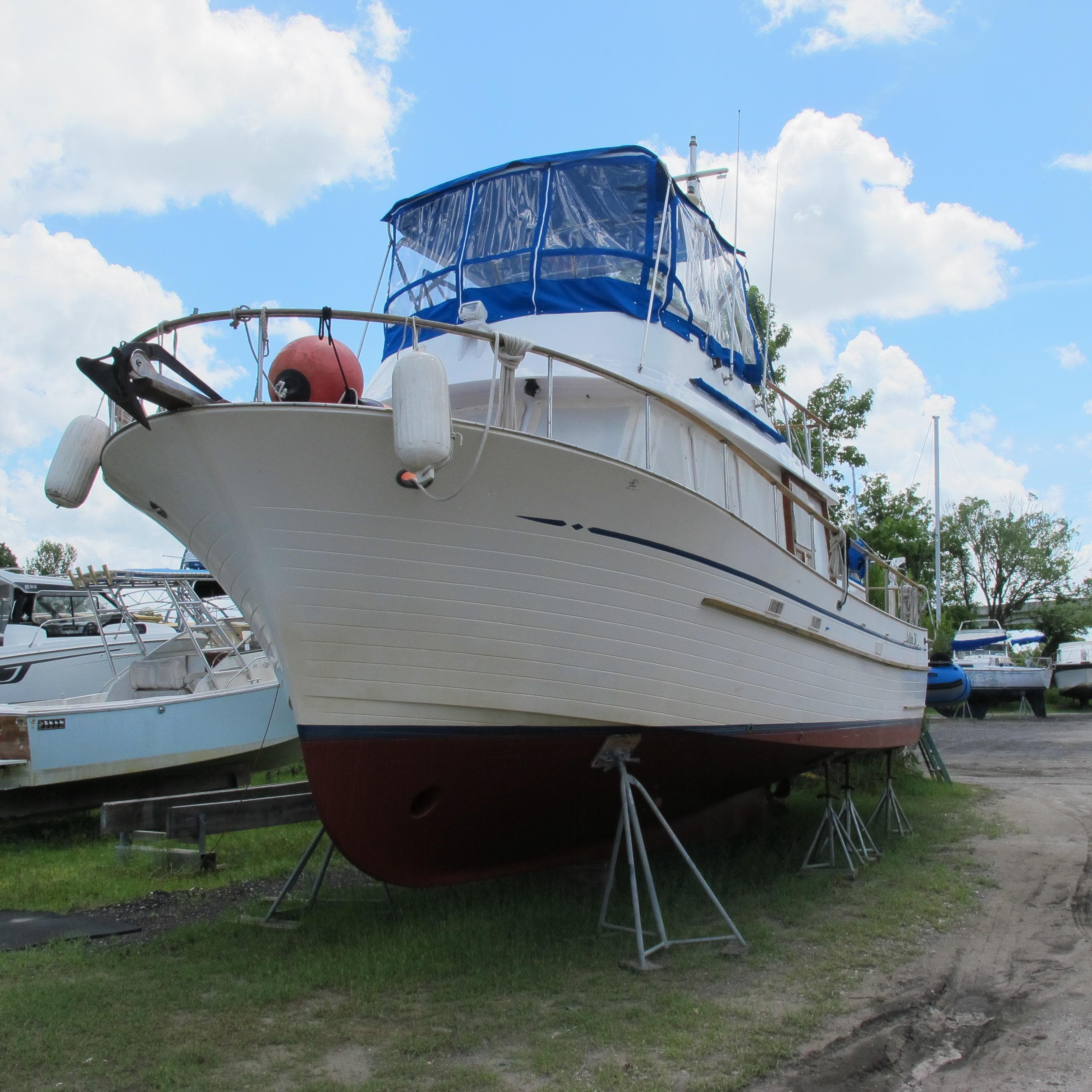 1981 Albin 36 boat on stands, blue canopy, clear sky background.