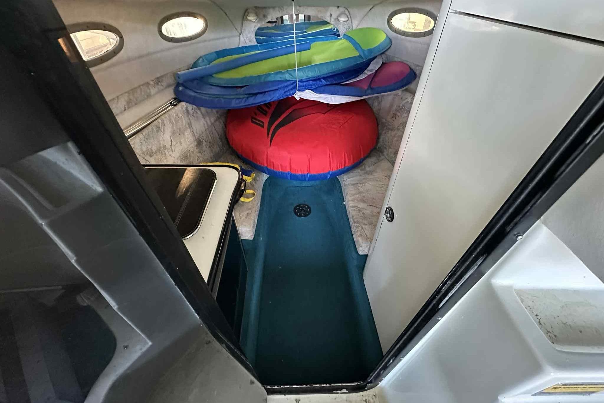 Interior of 1995 Genesis Boats 2505 with inflatables and compact cabin space.