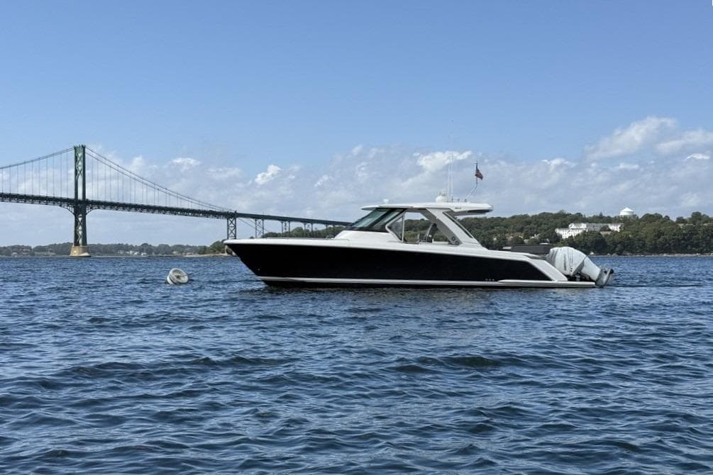 2021 Tiara Sport 38 LS boat on water near bridge, clear sky background.