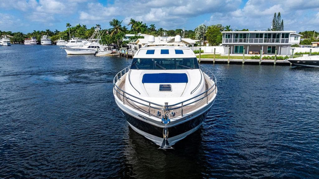Luxury 2010 Princess V78 yacht on a serene waterway, surrounded by modern homes.
