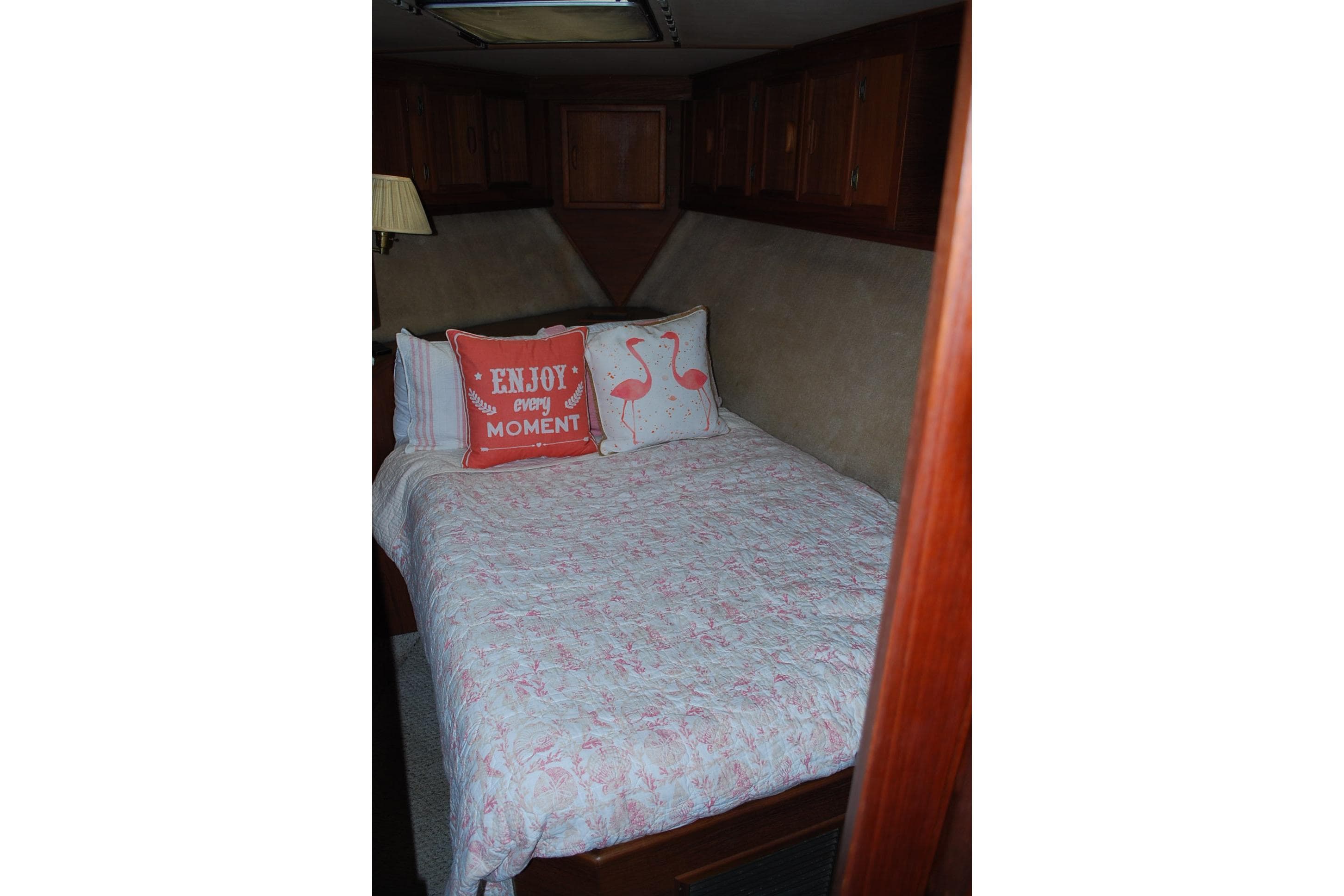 Cozy bedroom in 1987 Jersey Dawn boat with decorative pillows and wooden cabinets.