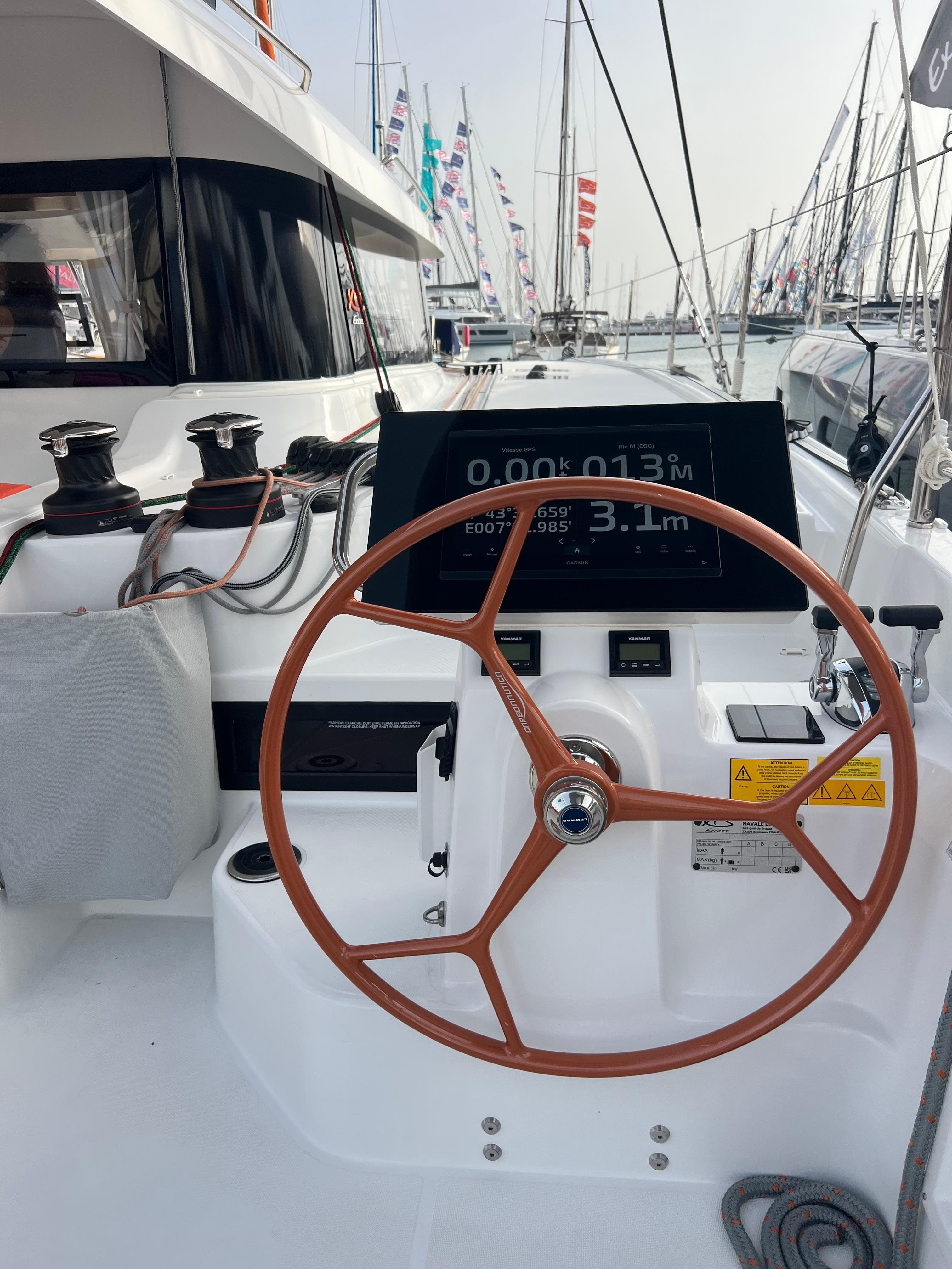 2024 Excess 14 yacht helm with wooden steering wheel and digital display.