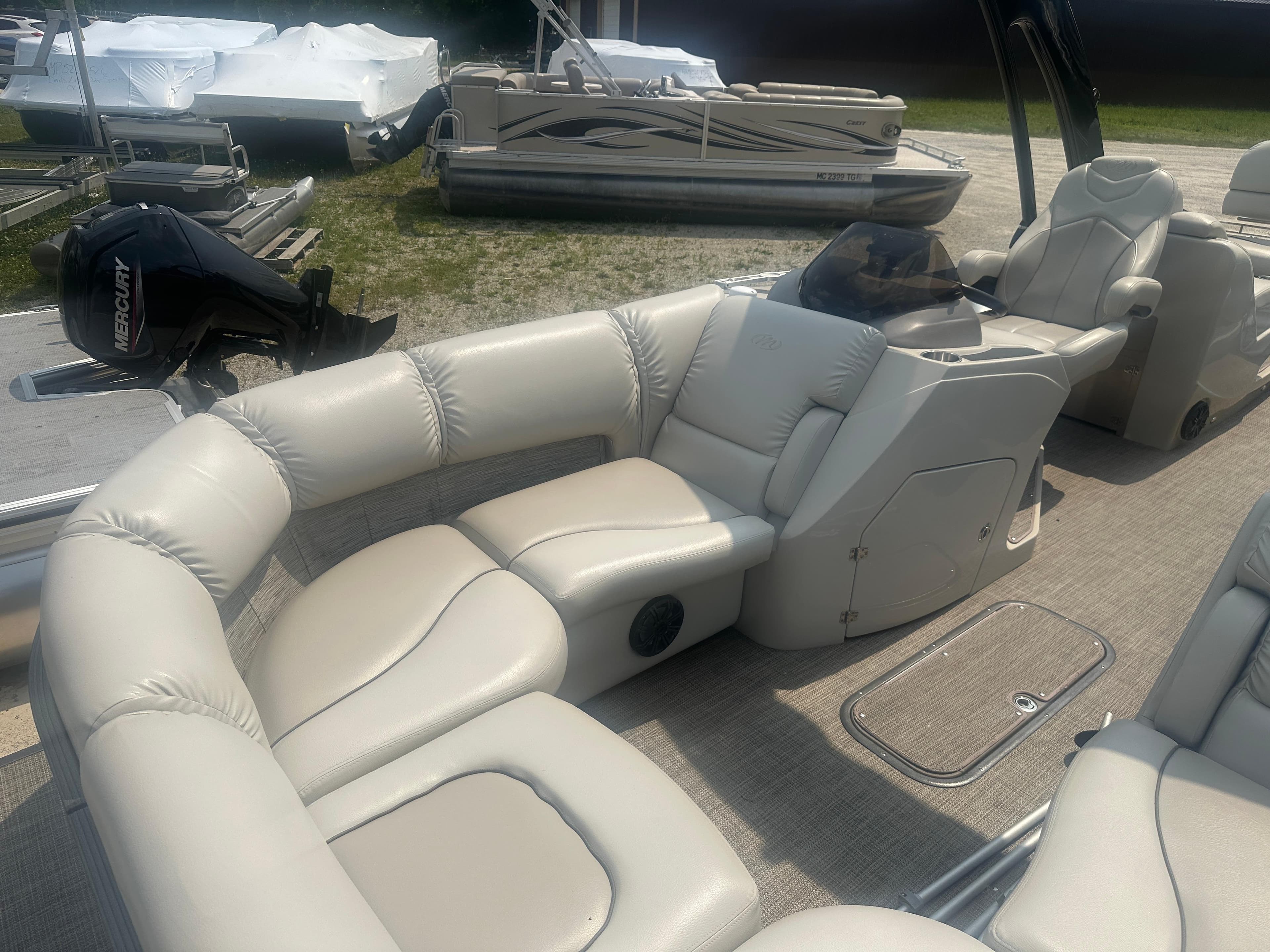 2016 Manitou 25 Legacy SRS pontoon boat with beige seating and Mercury outboard motor.
