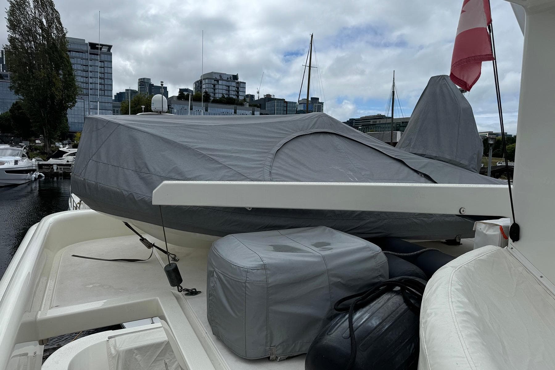 Covered Dyna Laguna boat on deck, urban marina backdrop, overcast sky.