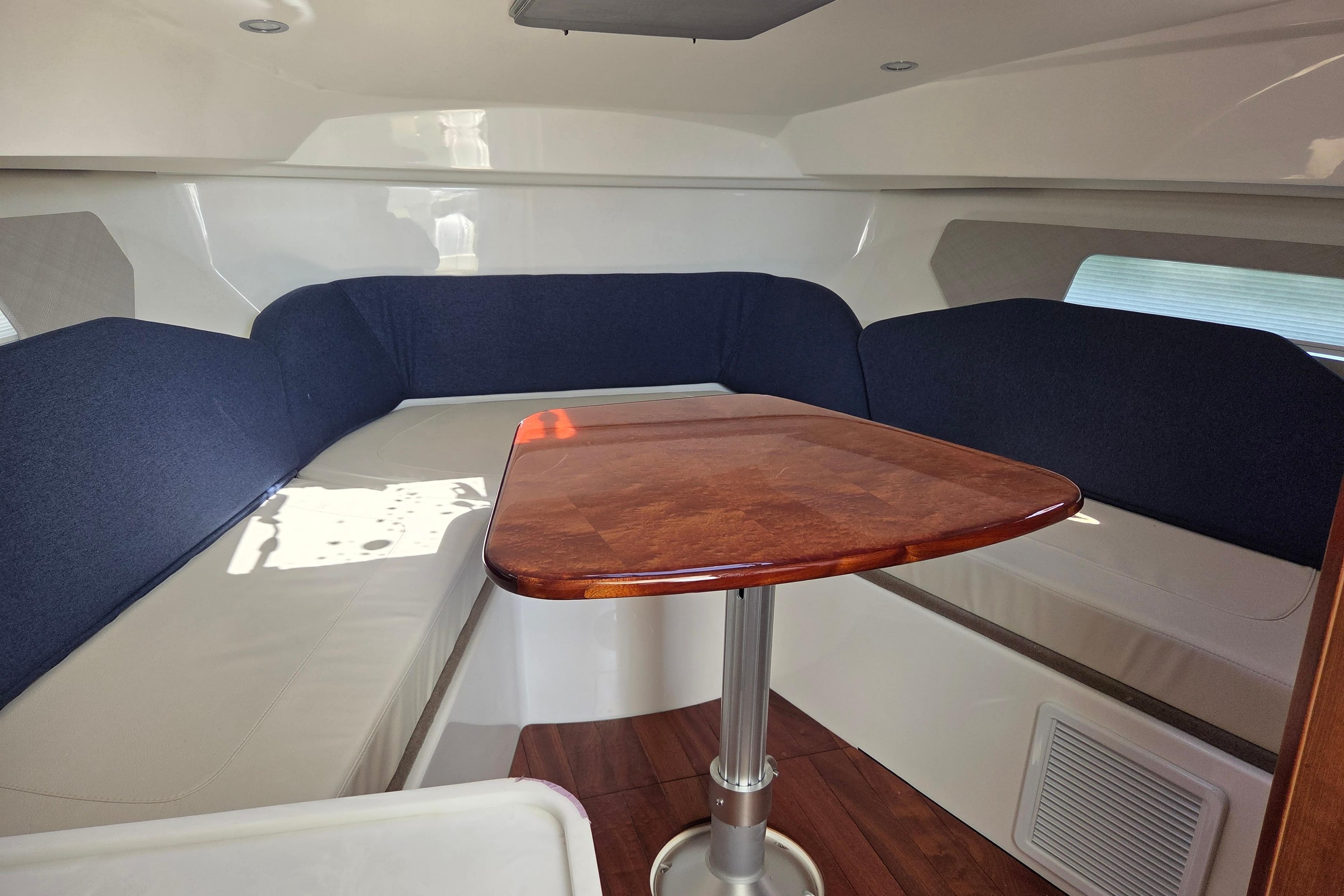 Interior of 2026 Pursuit OS 325 Offshore boat with wooden table and cushioned seating.