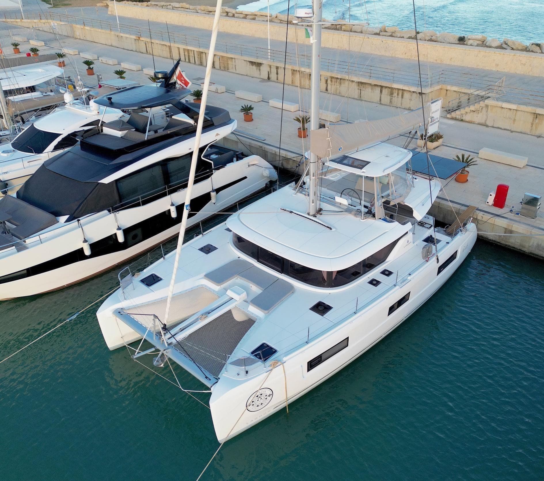 2023 Lagoon 46 catamaran docked in marina, featuring sleek design and spacious deck.