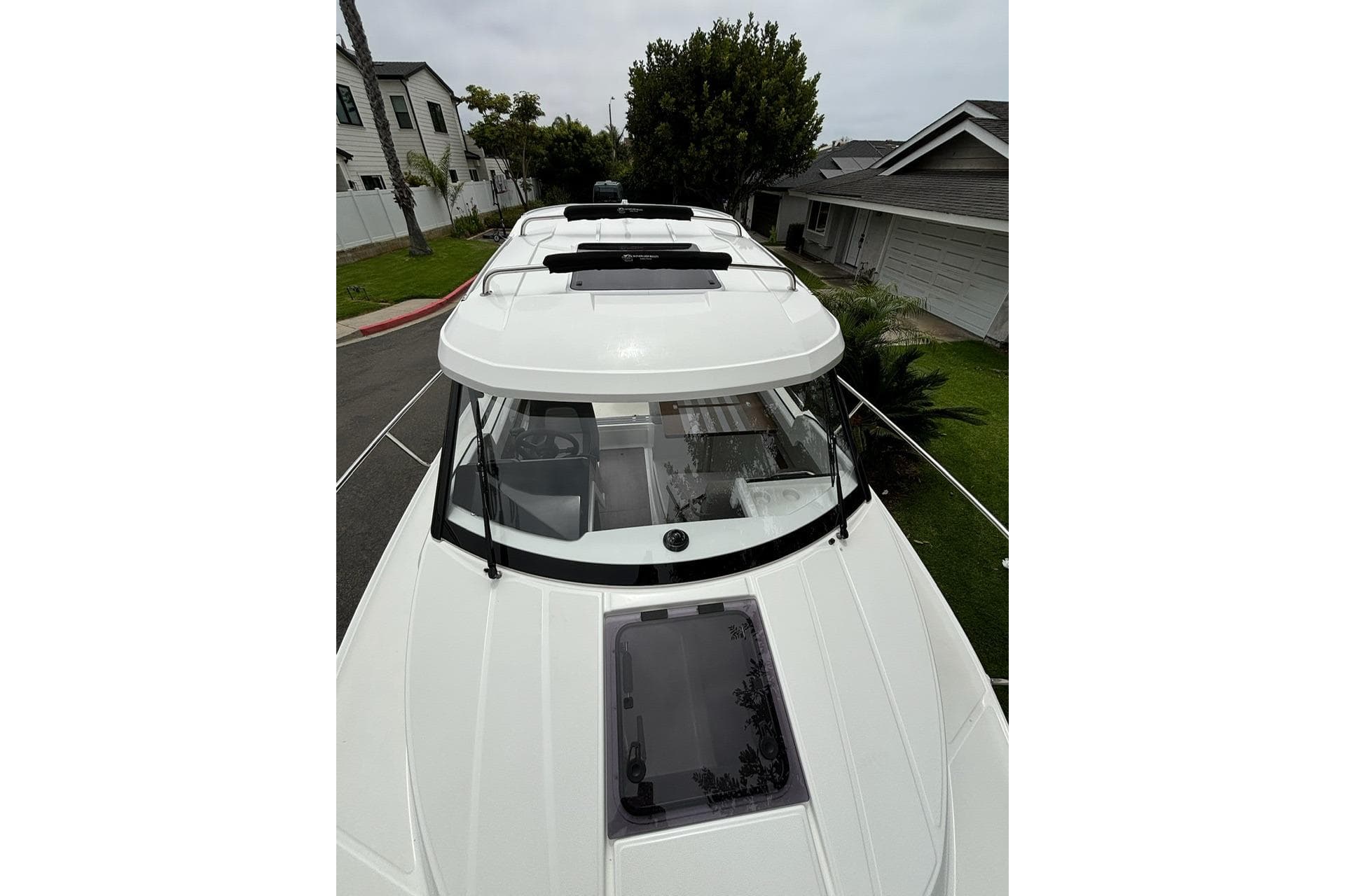2023 Jeanneau NC Weekender 695 Series 2 boat, top view, parked in residential area.