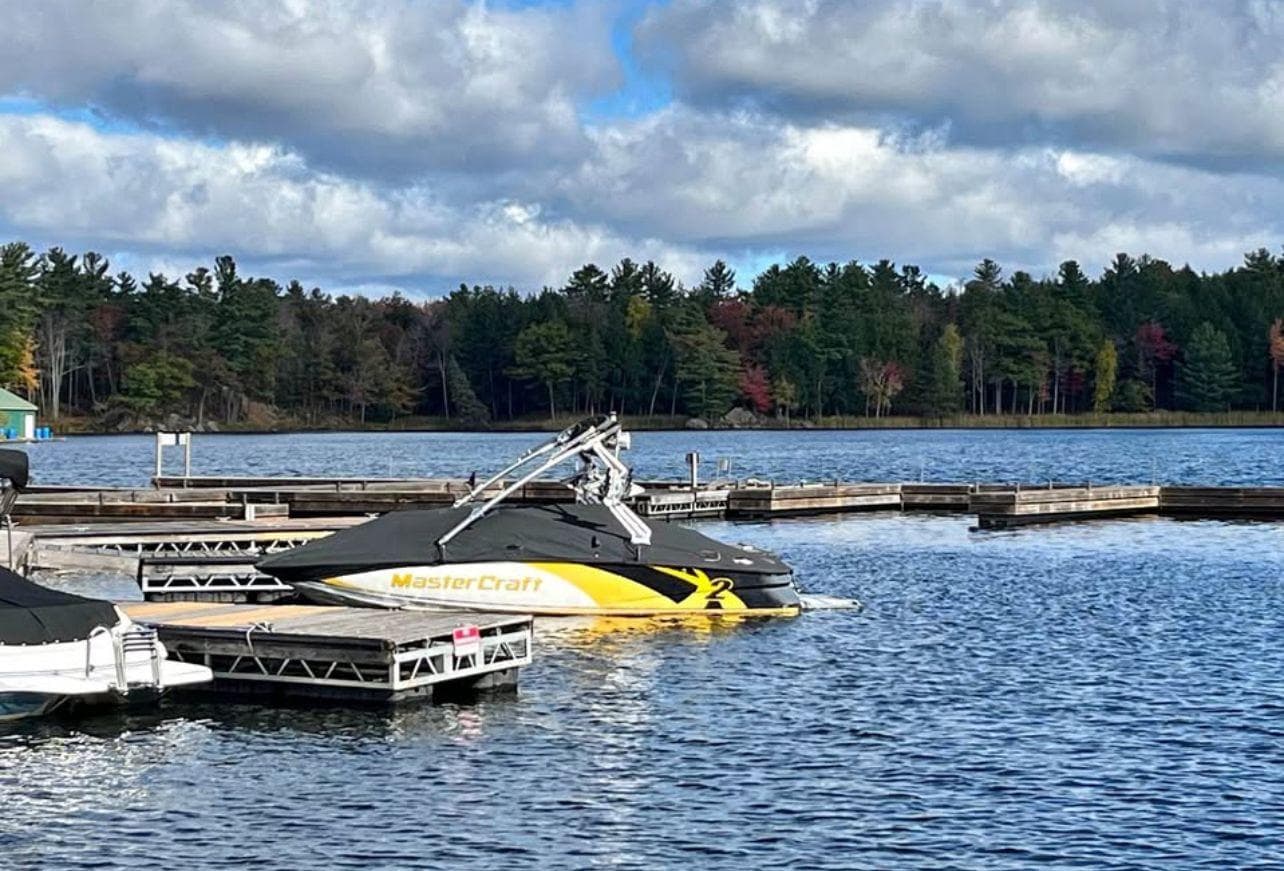 2011 MasterCraft X2 boat docked on a scenic lake with forested background.