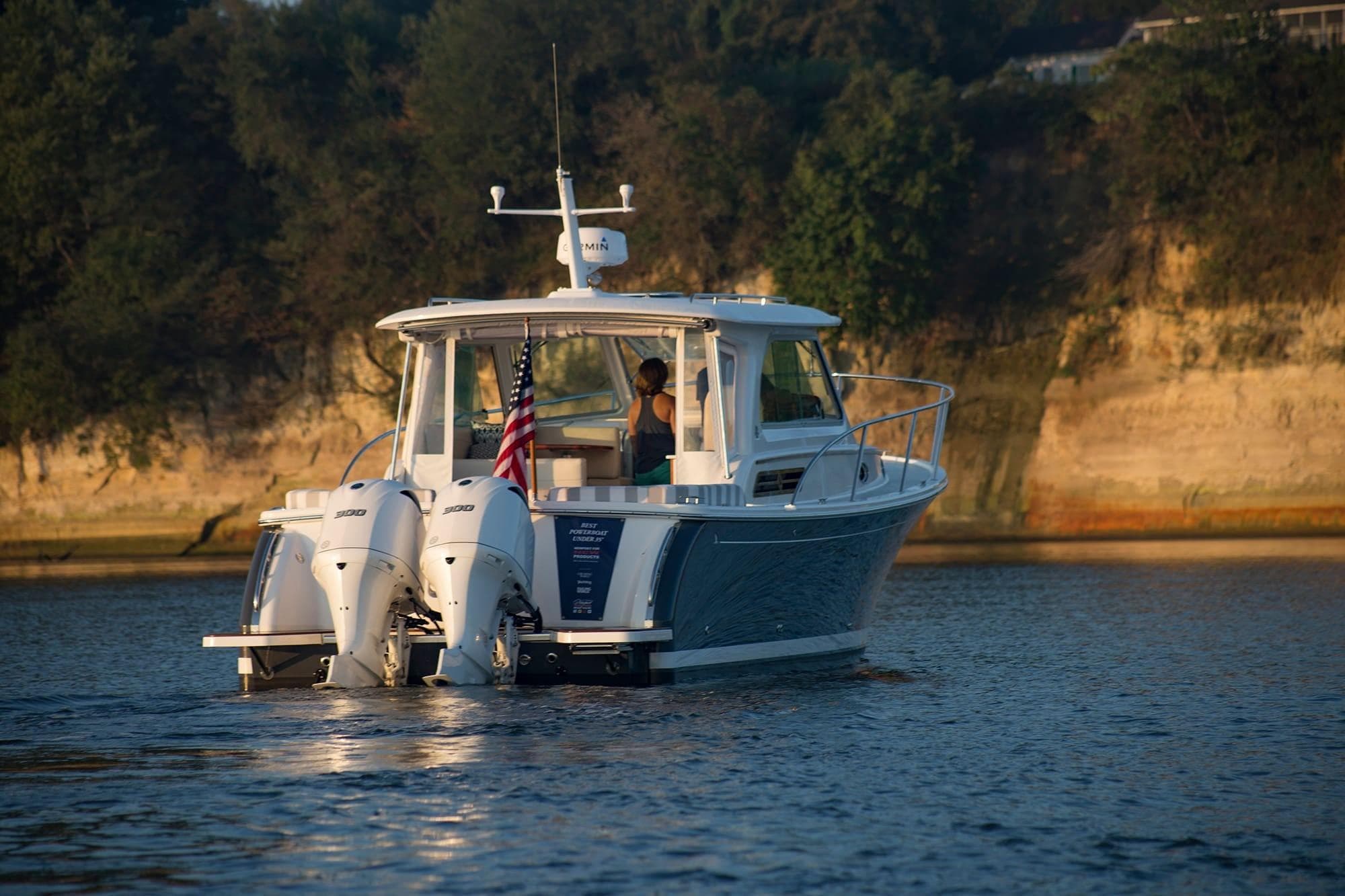 2024 Back Cove 34O boat cruising on a lake with scenic cliffs in the background.