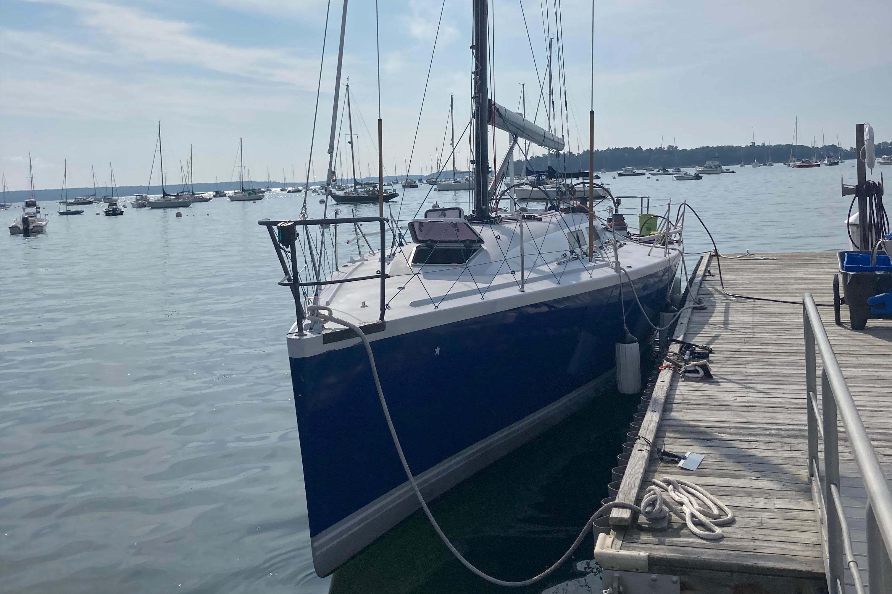 Sailboat docked at marina, Tripp 47 model, 1995, calm waters, clear sky.