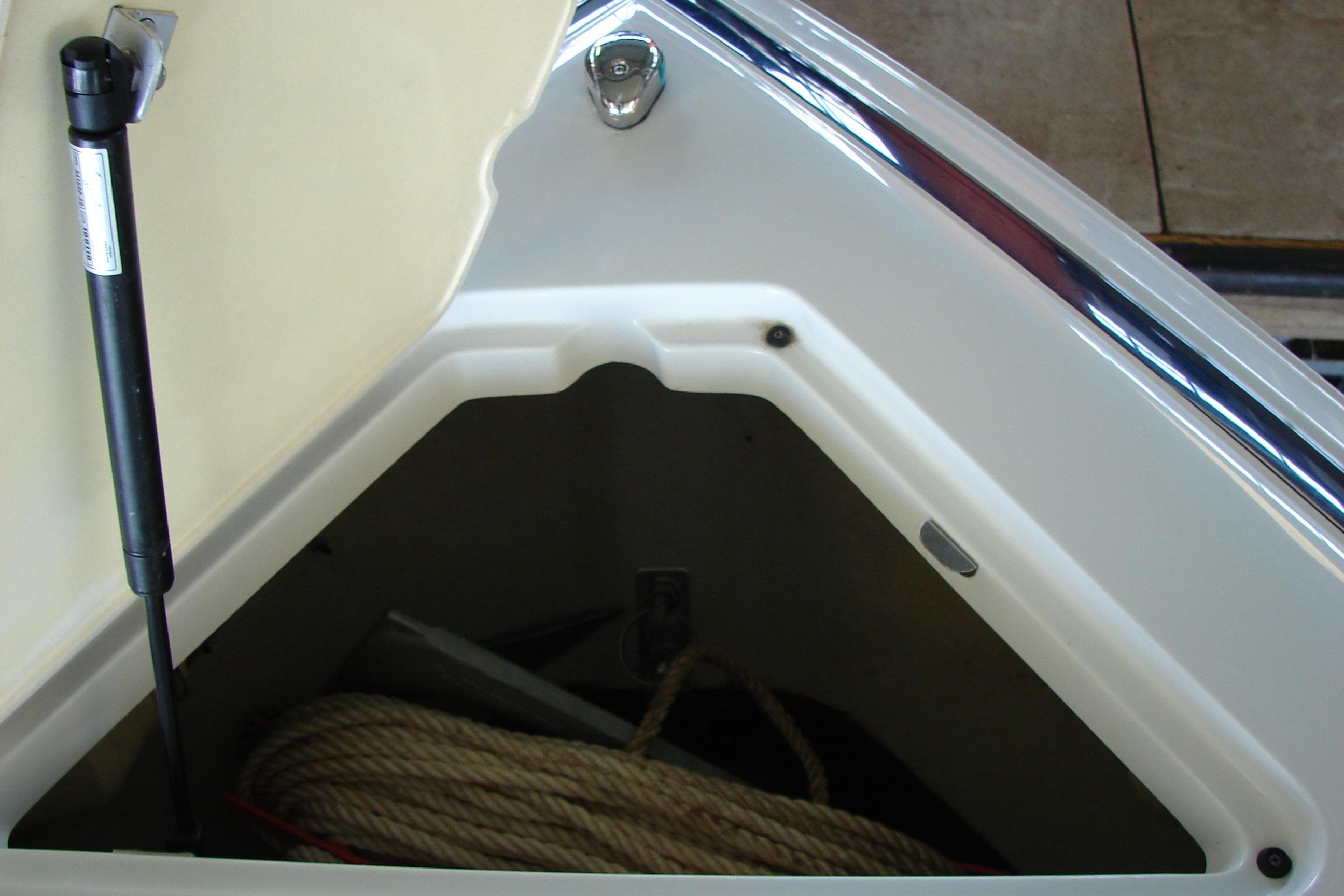 Open storage compartment on 2011 Cobalt 232 boat with rope inside.