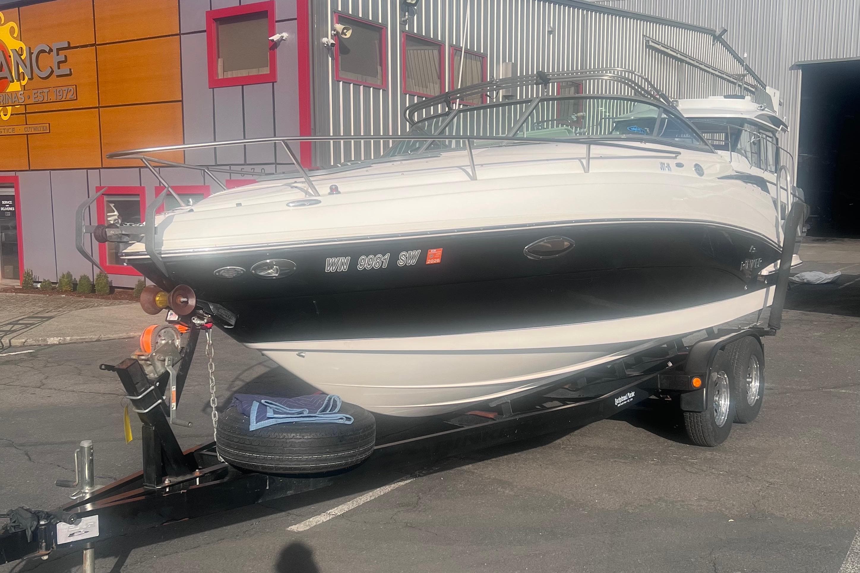 2007 Rinker 230 Captiva Atlantic boat on trailer, parked outside a building.