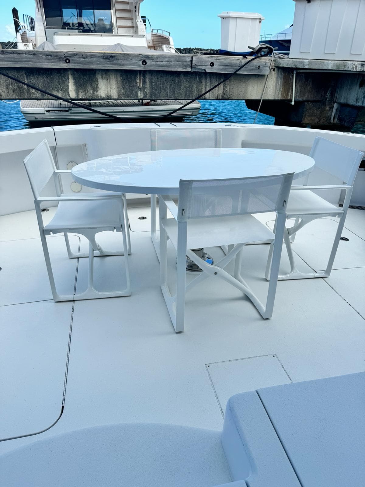 2009 Hatteras 60 Convertible yacht with white outdoor dining set on deck.
