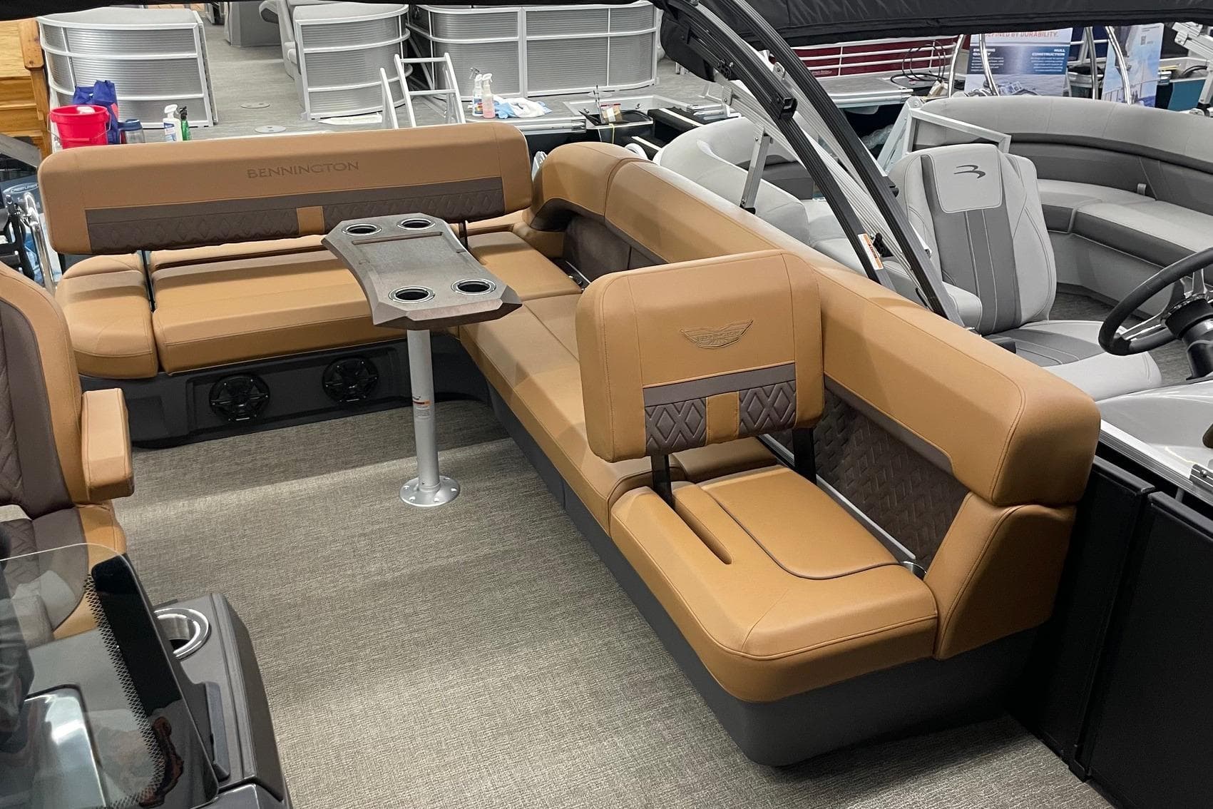 2025 Bennington 22 M CRUISE boat interior with tan seating and cupholder table.