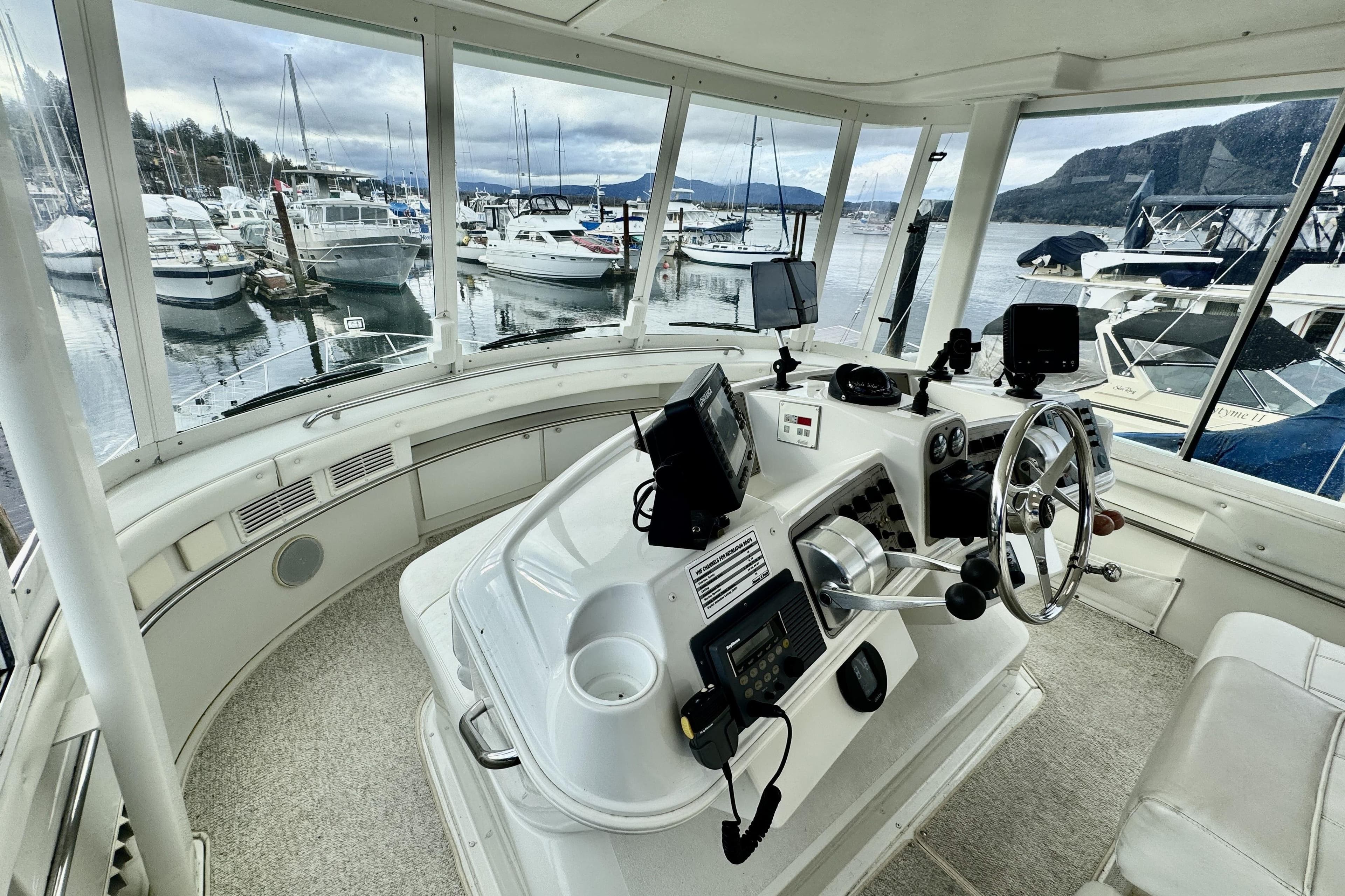 Interior view of a 1997 Carver 500 Cockpit Motor Yacht helm with marina backdrop.