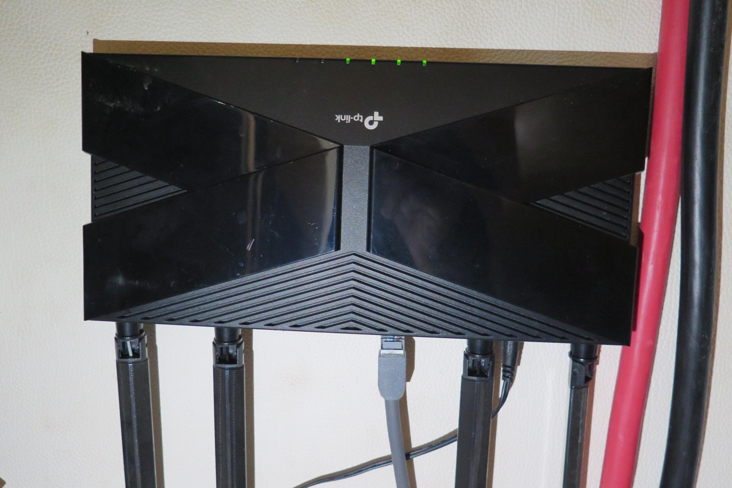 TP-Link router mounted on wall, connected with multiple cables.