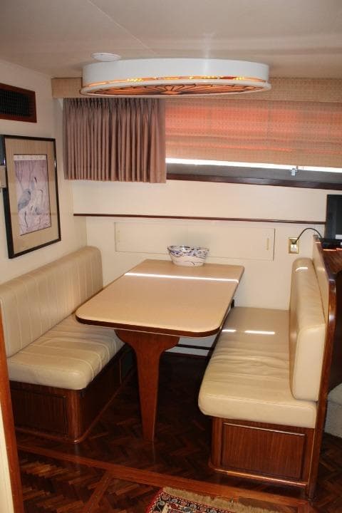 1985 Hatteras 58 Motor Yacht interior with cozy dining nook and elegant wood finishes.