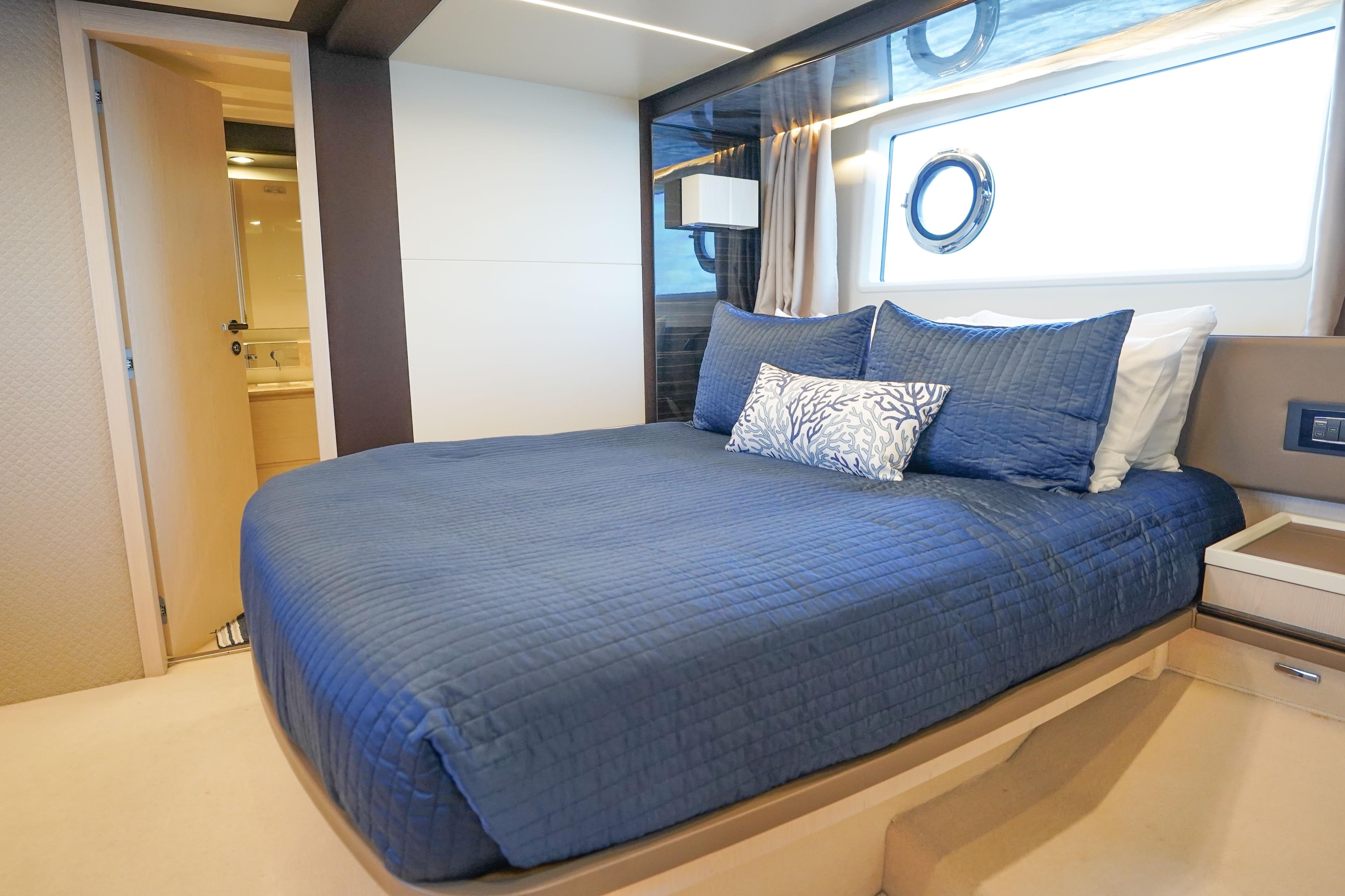 Luxurious bedroom interior of 2017 Azimut 66 Flybridge yacht with blue bedding.