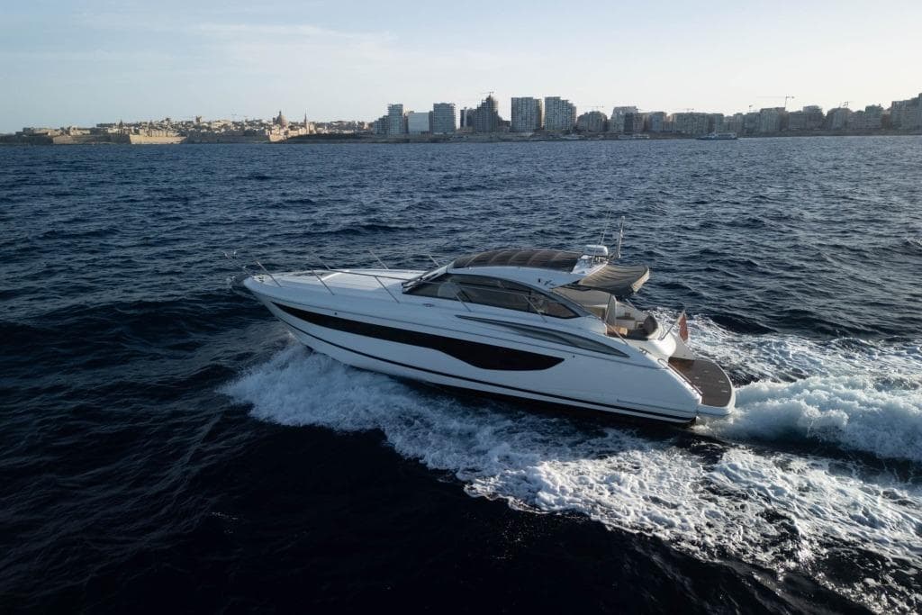 2021 Princess V40 yacht cruising on open sea near city skyline.