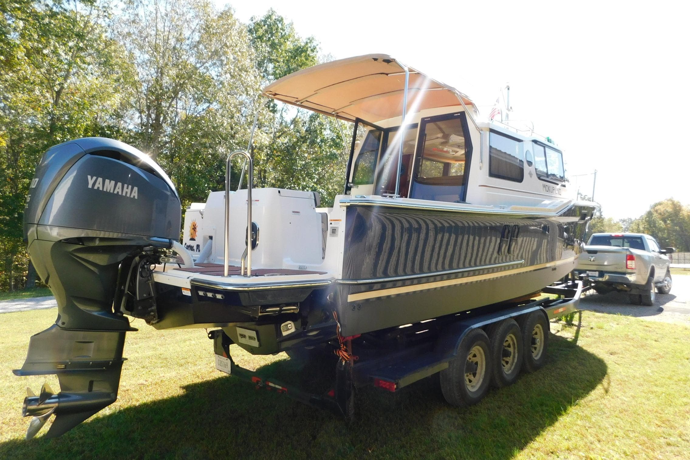 2022 Ranger Tugs R-27 boat on trailer with Yamaha outboard motor, parked on grass.