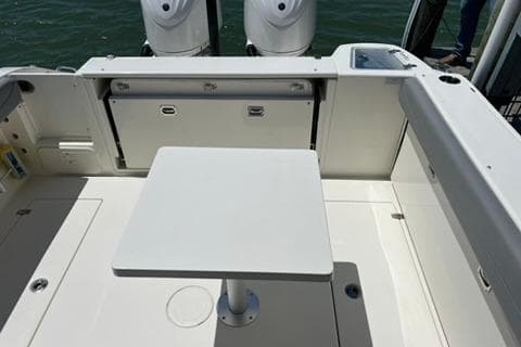 2024 Cobia 280 Dual Console boat interior with table and twin engines.
